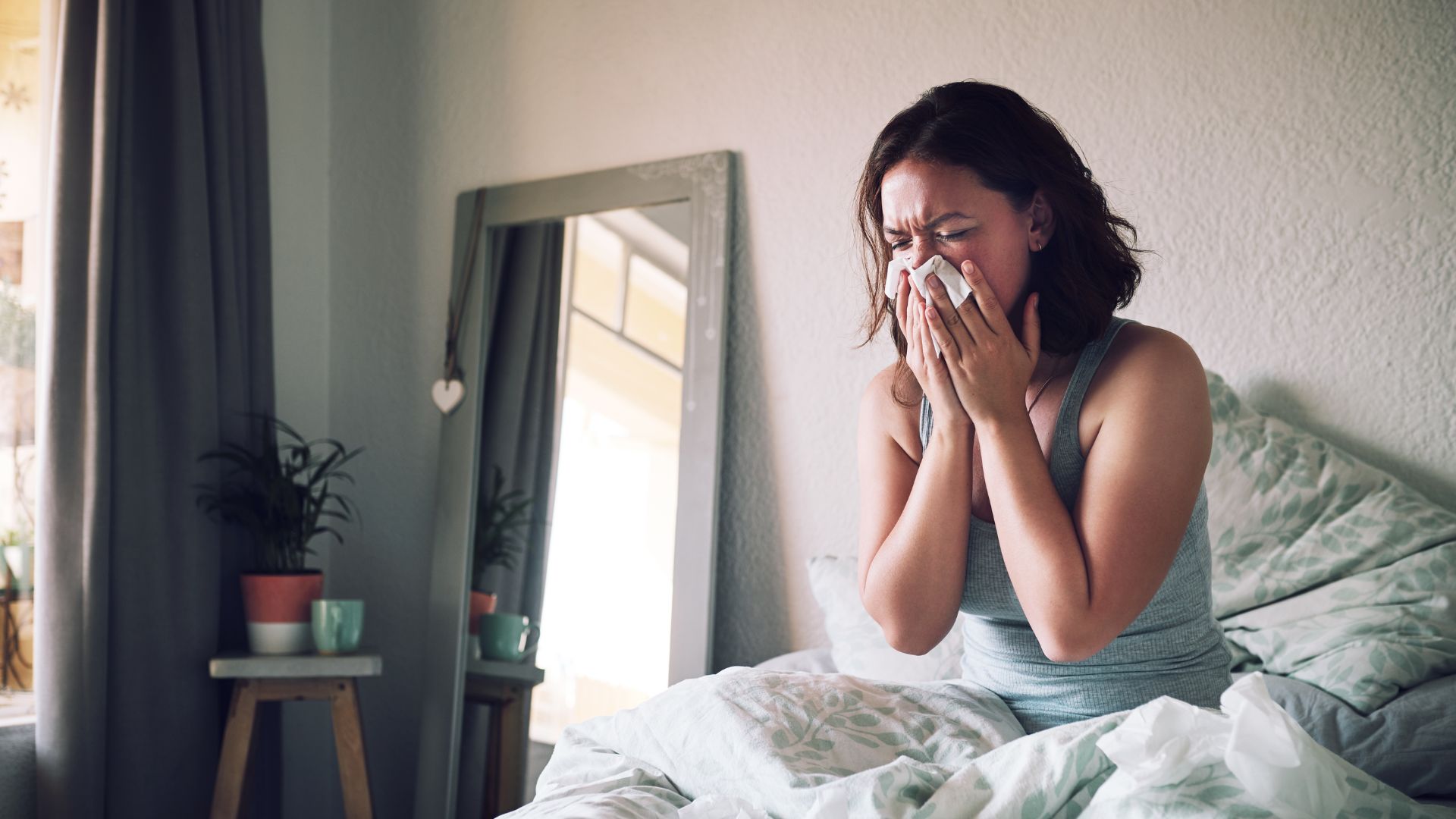 Femme se mouchant au lit à cause d'allergies