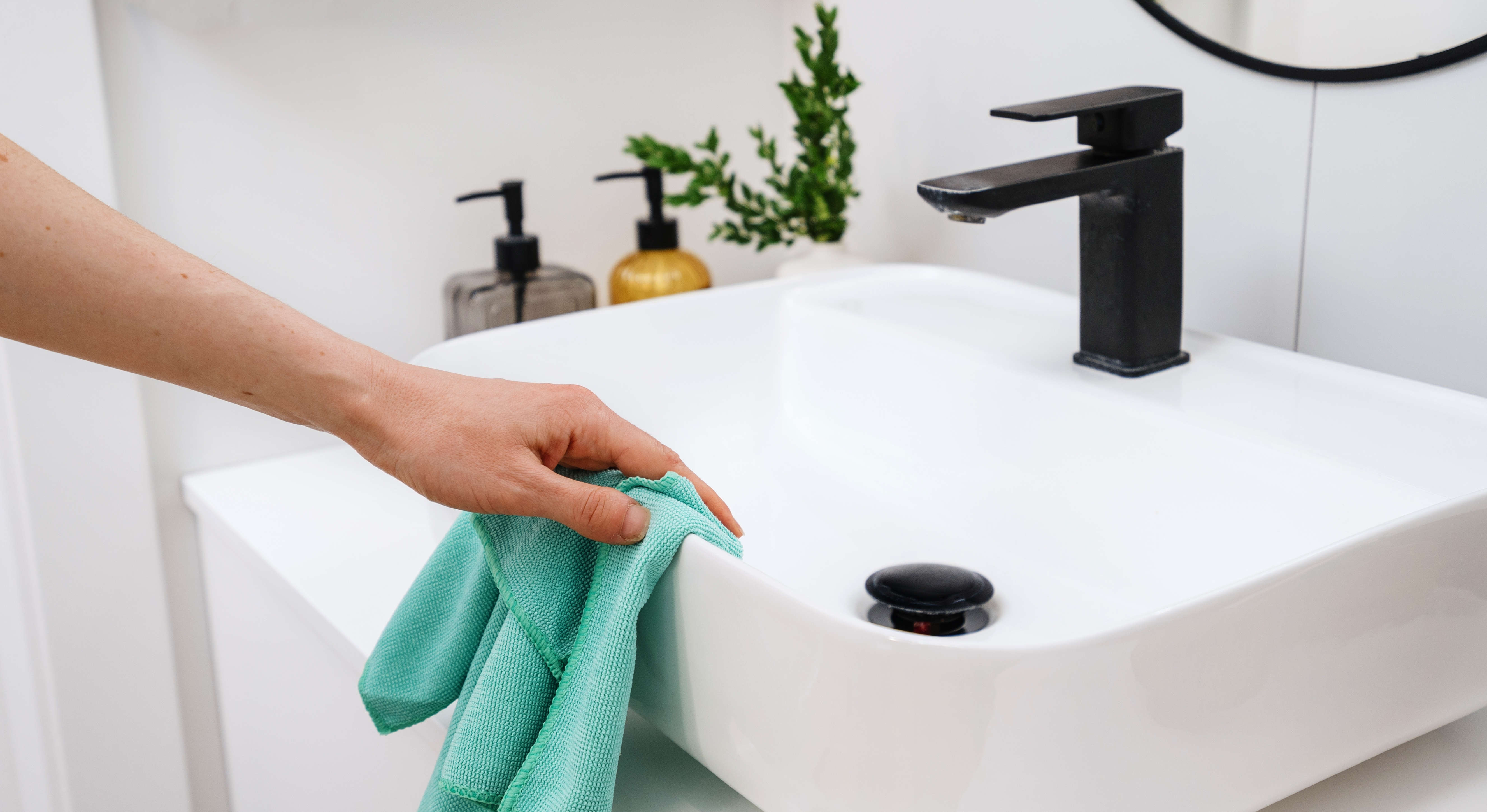 Femme nettoyant un lavabo de salle de bain avec un chiffon en microfibre
