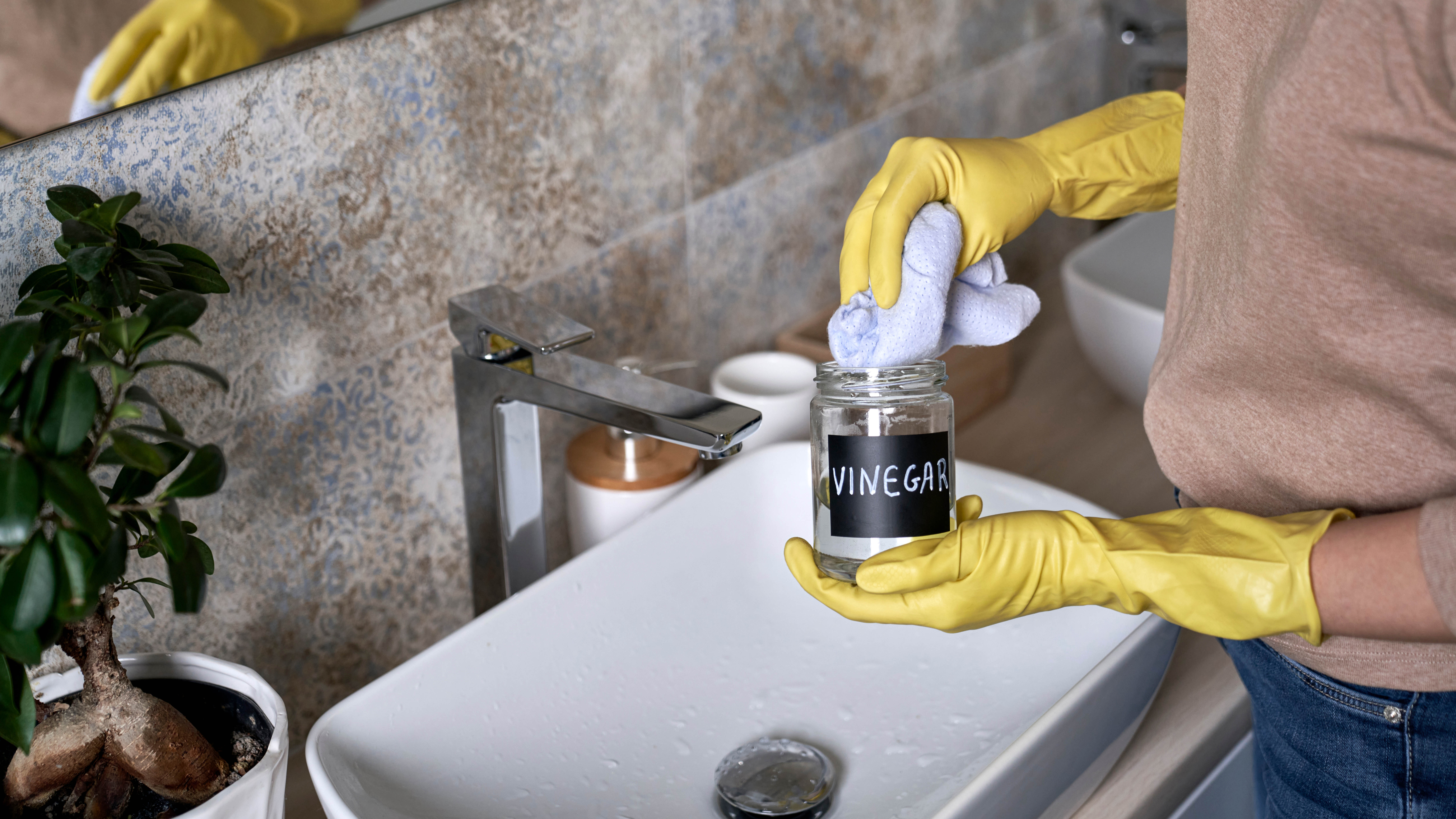 Quelqu'un portant des gants nettoyant une salle de bain avec du vinaigre