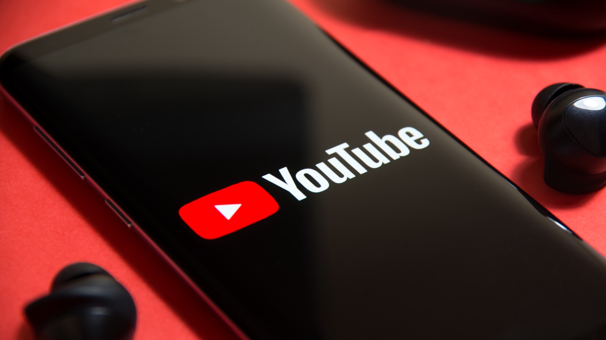 Logo YouTube sur un smartphone entouré d'écouteurs