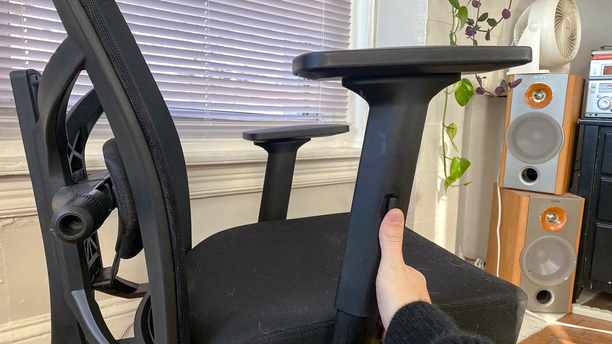 Une main ajustant l'accoudoir sur une chaise de bureau
