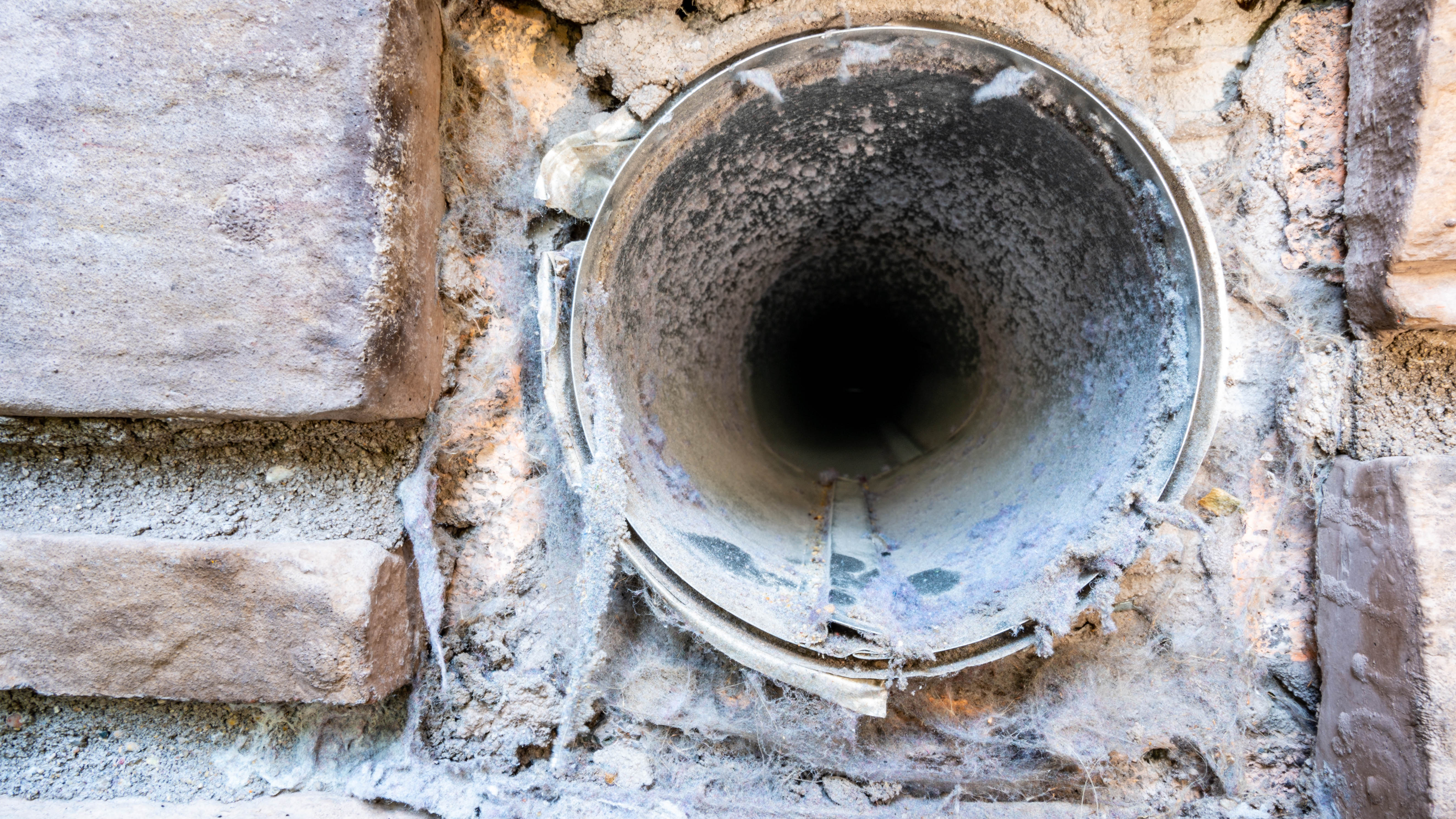 L'extérieur d'un évent de sécheuse sale rempli de peluches