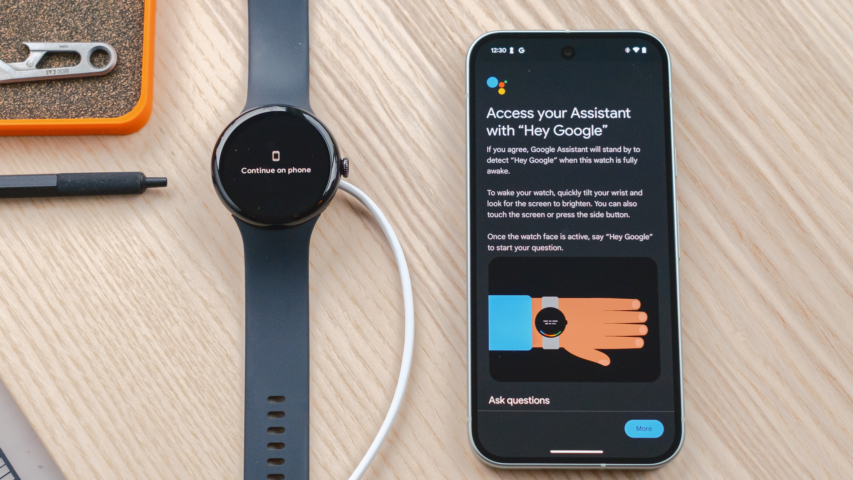Google Pixel Watch 3 posée sur un bureau en bois à côté d'un smartphone Pixel 9 affichant l'écran de configuration vocale de l'Assistant Google