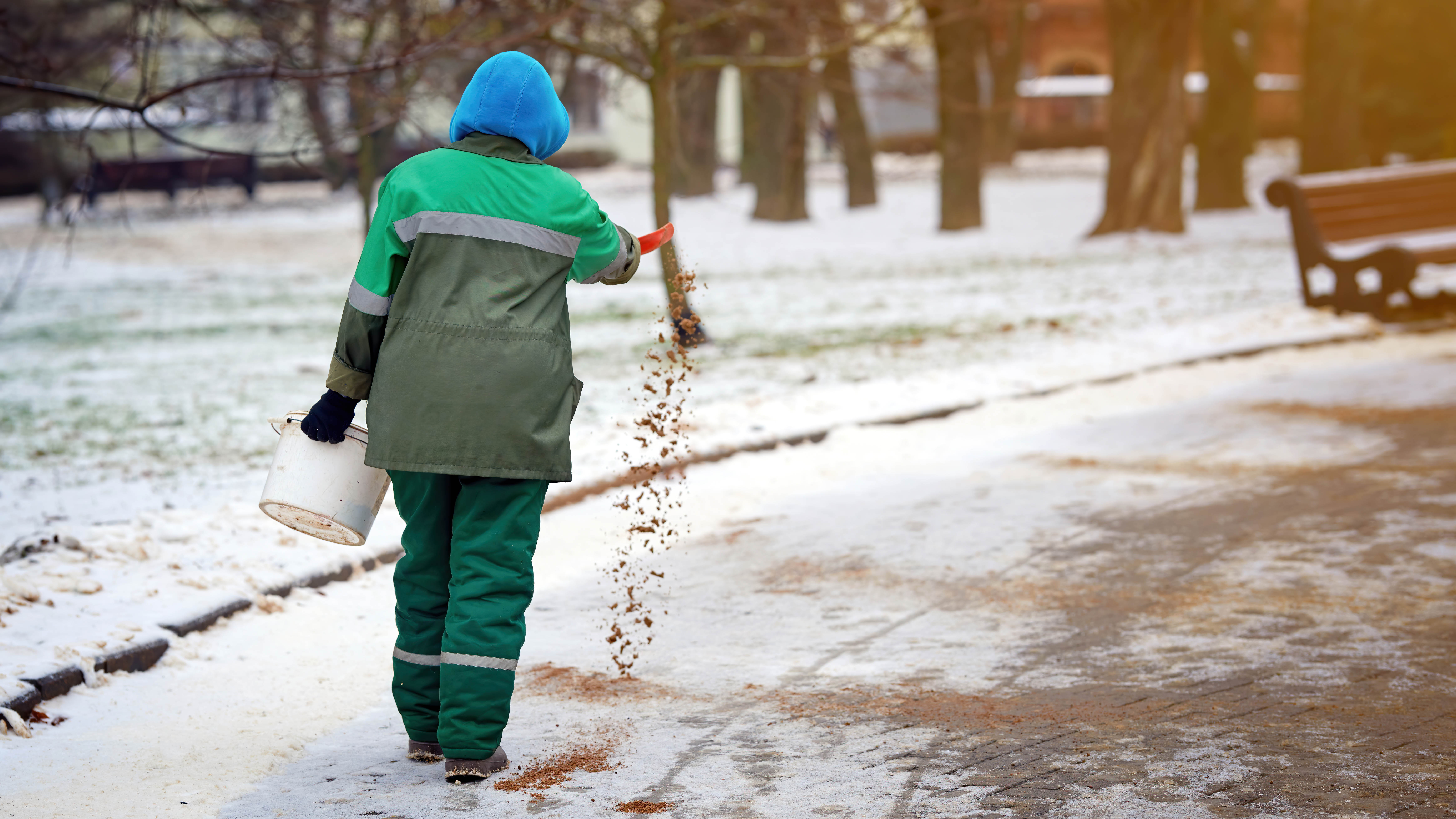 Homme répandant du sable sur la neige