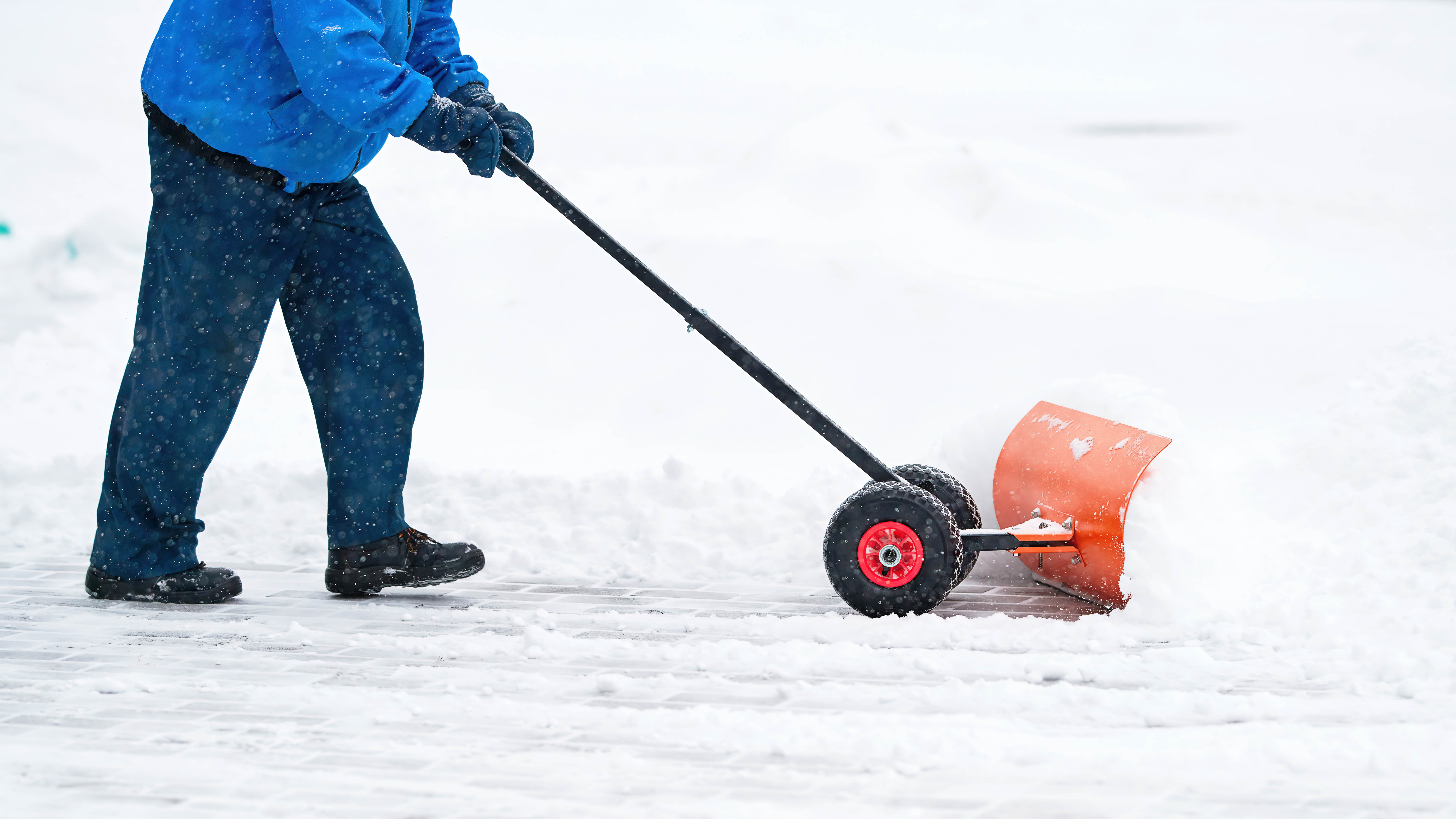 Homme utilisant un pousse-neige dans la neige