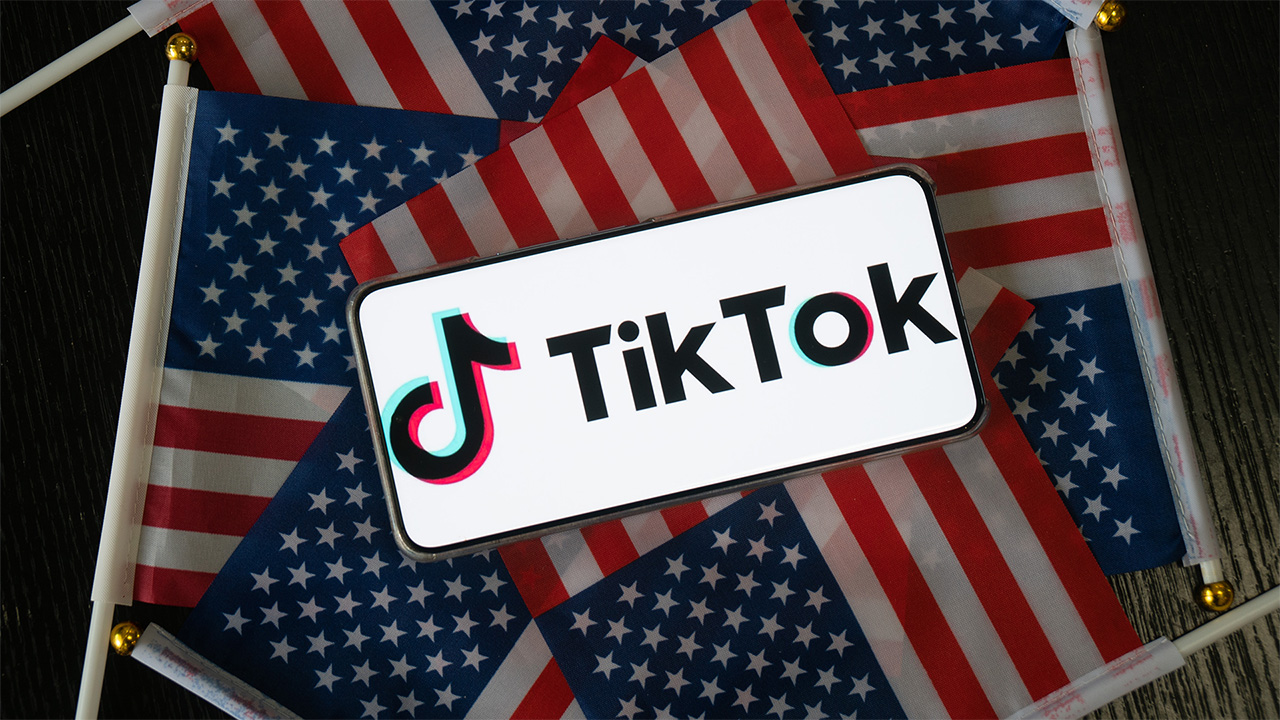 Smartphone affichant le logo TikTok sur un lit de drapeaux américains