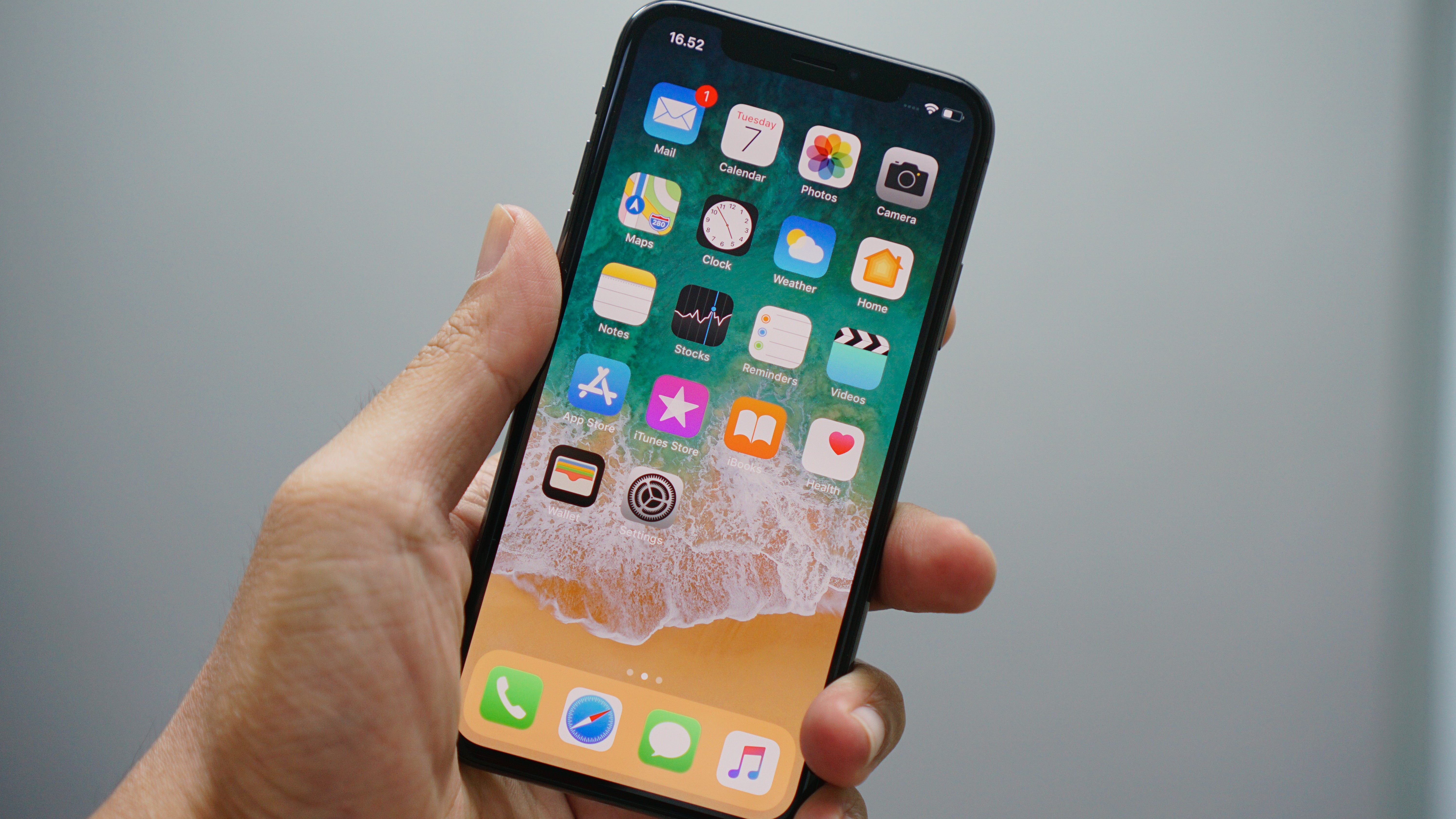 Une personne tenant un iPhone X déverrouillé, affichant son écran d'accueil