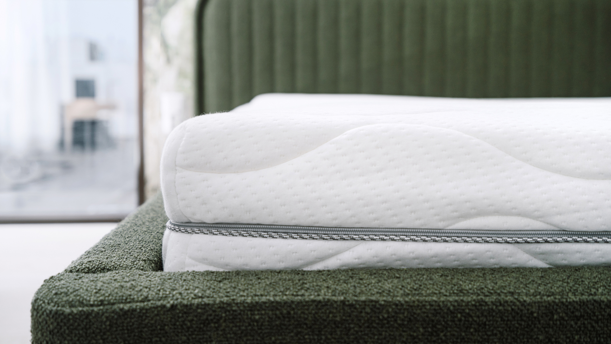 Un matelas blanc à fermeture éclair sans fibre de verre photographié sur un cadre de lit en boucle vert forêt