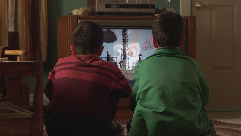 Luca Villacis en tant que jeune Mike / Eddie alors que les frères regardent Candle Cove dans Channel Zero: Candle Cove