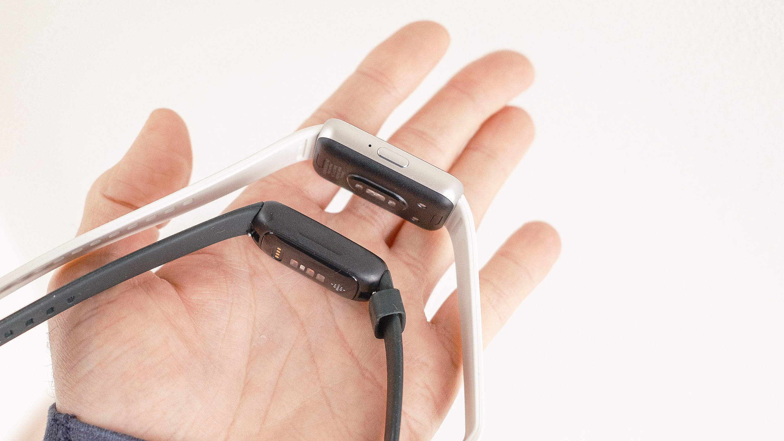 Gros plan du Samsung Galaxy Fit3 à côté du Fitbit Inspire 3 dans la main d'un utilisateur