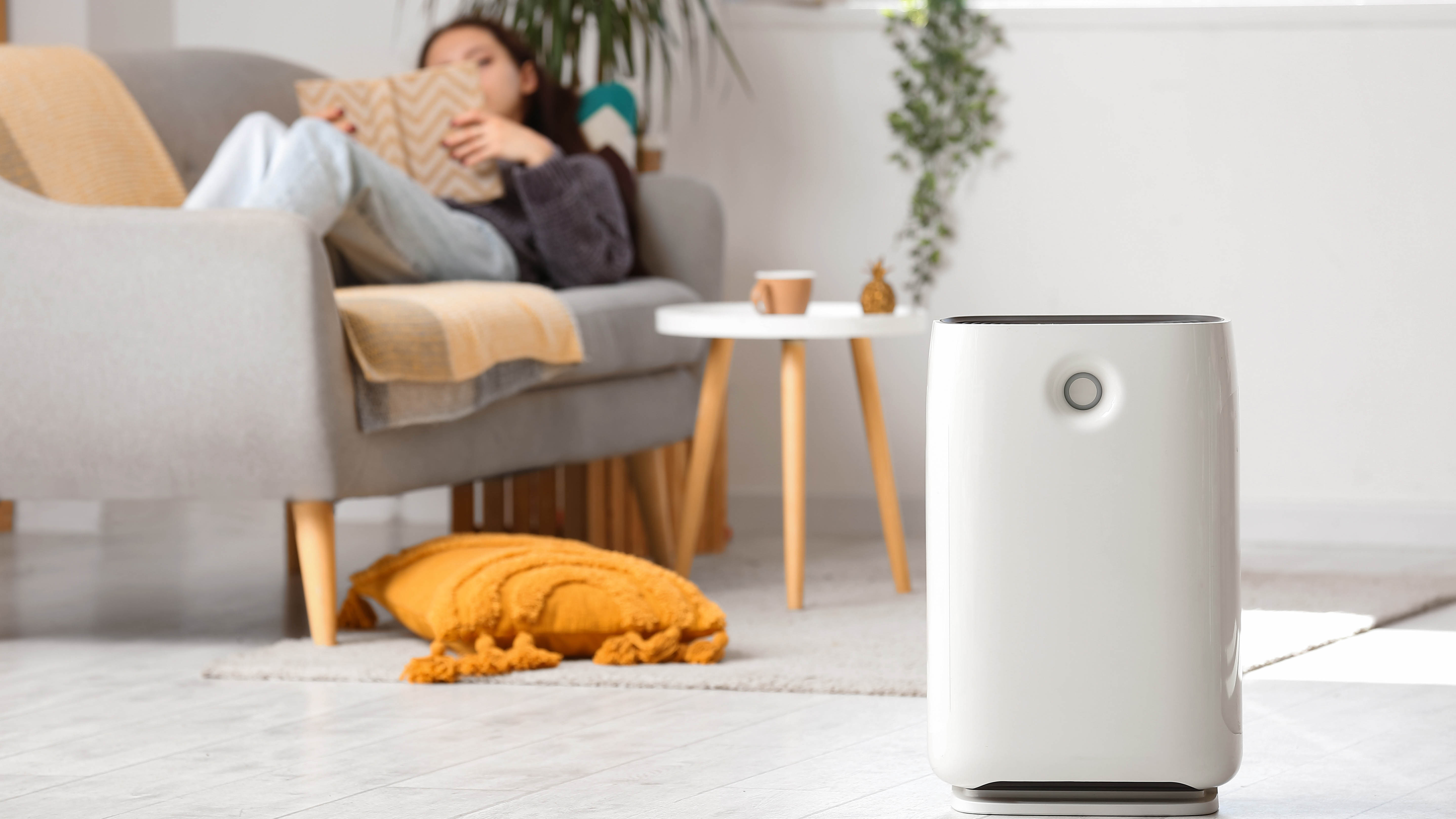 Purificateur d'air dans le salon avec une femme lisant un livre sur le canapé