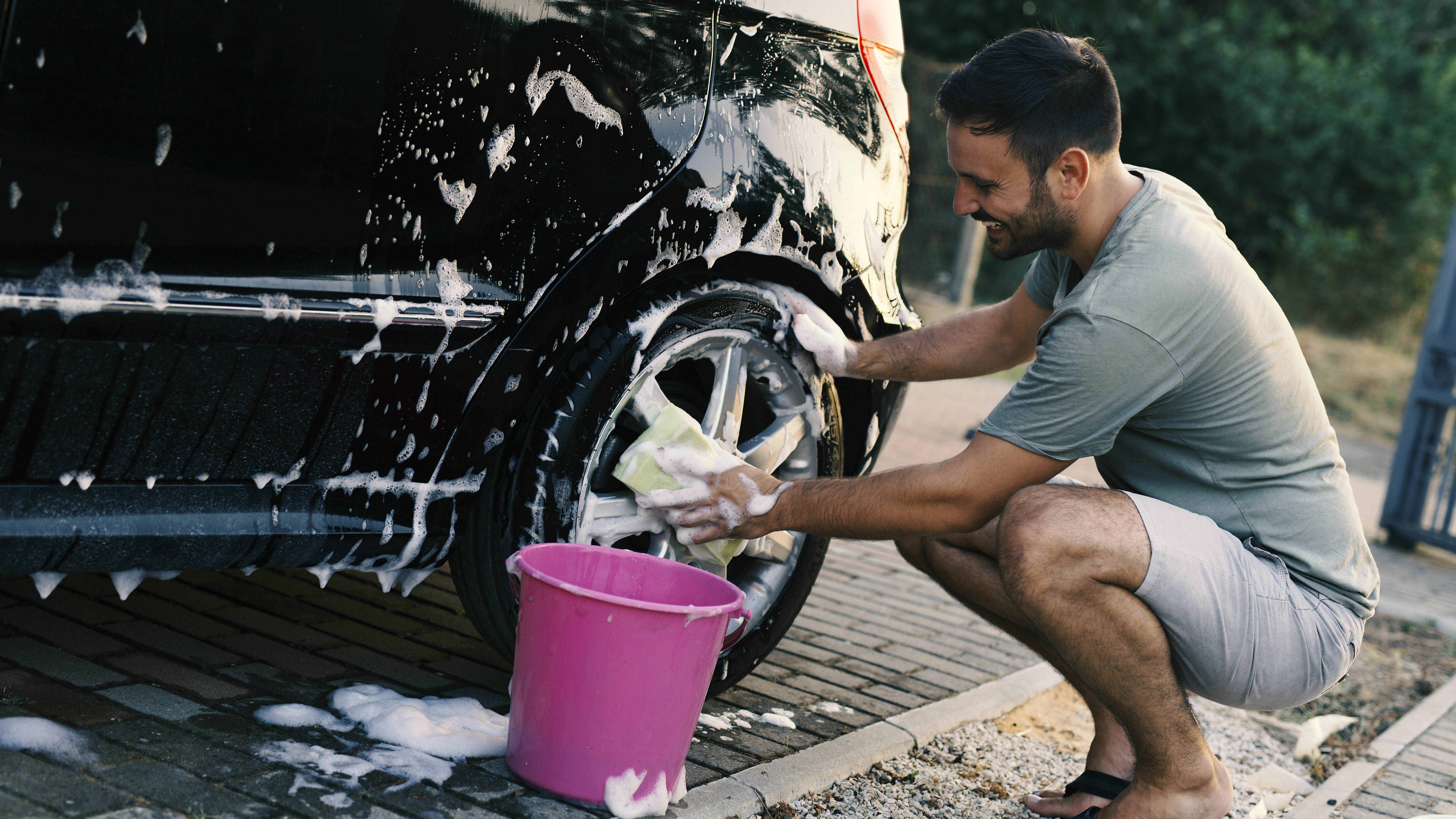 Homme lavant une voiture noire avec un tissu