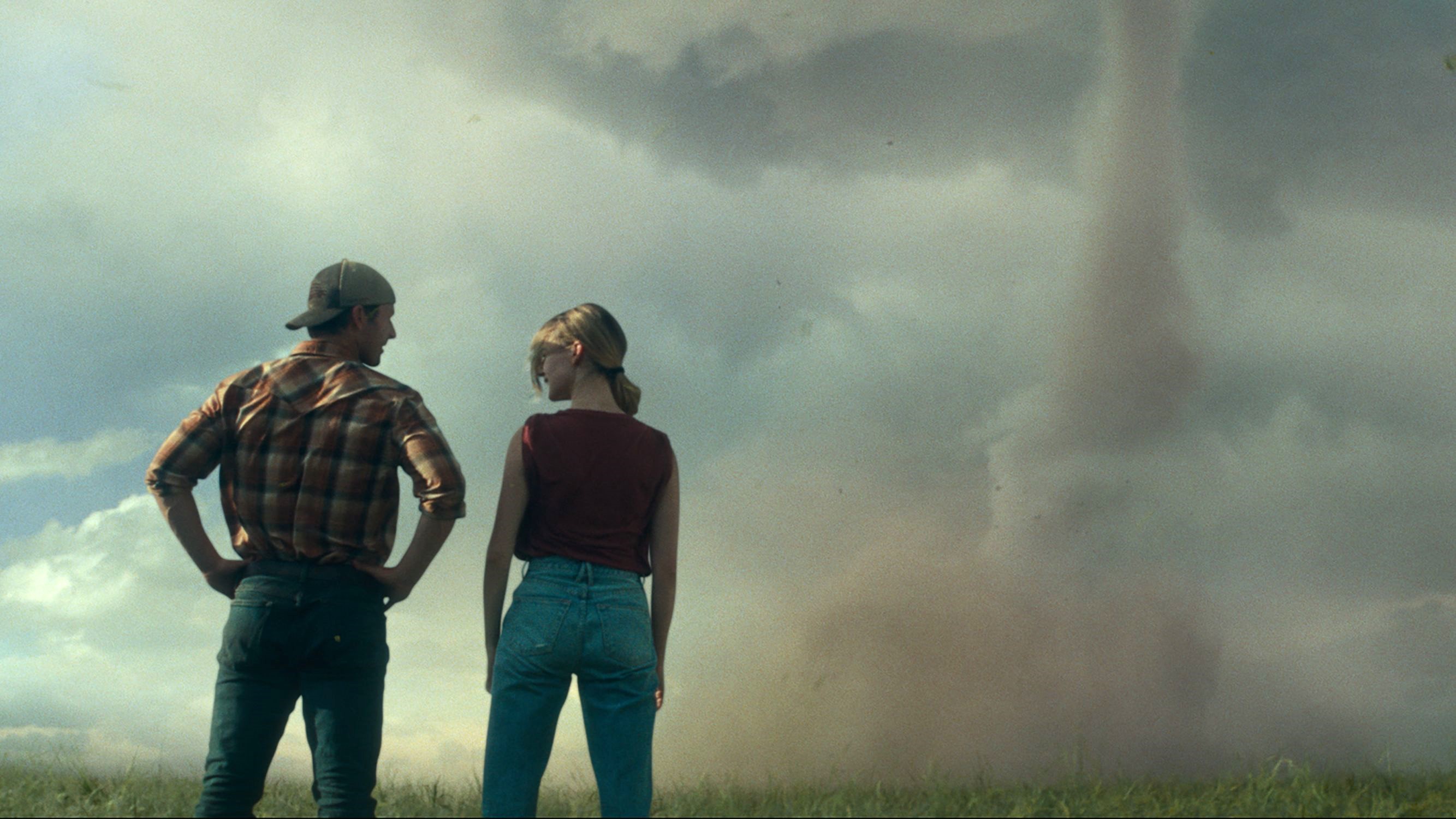 Glen Powell et Daisy Edgar-Jones face à la caméra en regardant une tornade