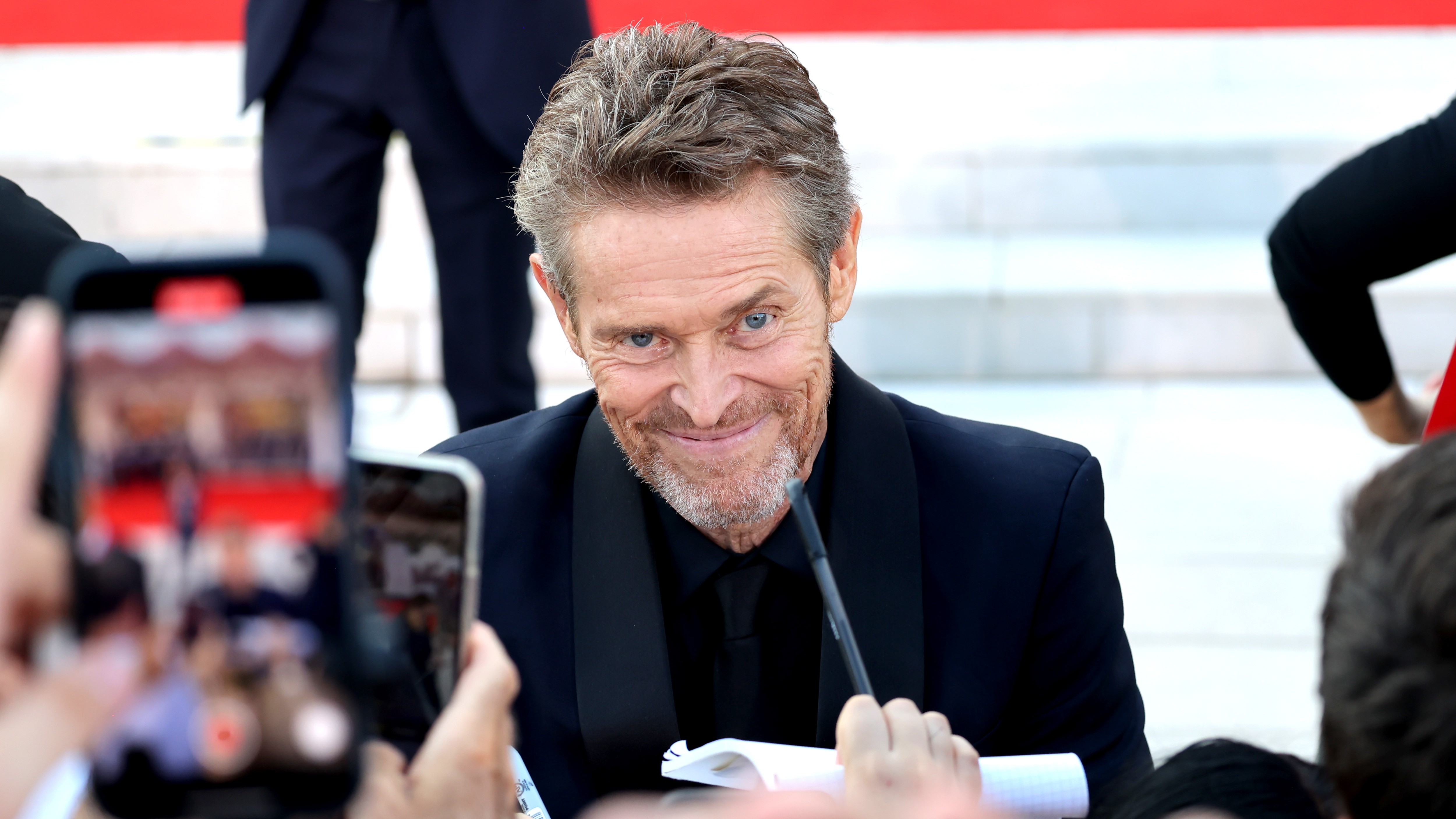 Willem Dafoe signe des autographes pendant un tapis rouge pour
