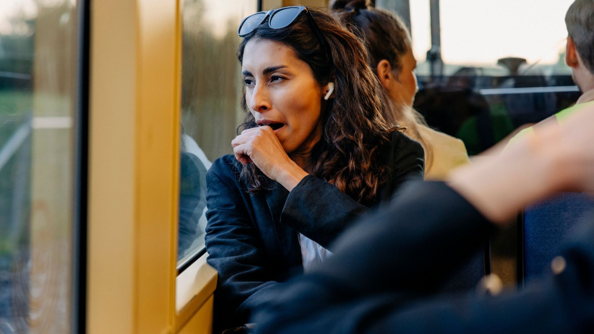 Une femme fatiguée dans un train regardant par la fenêtre et bâille