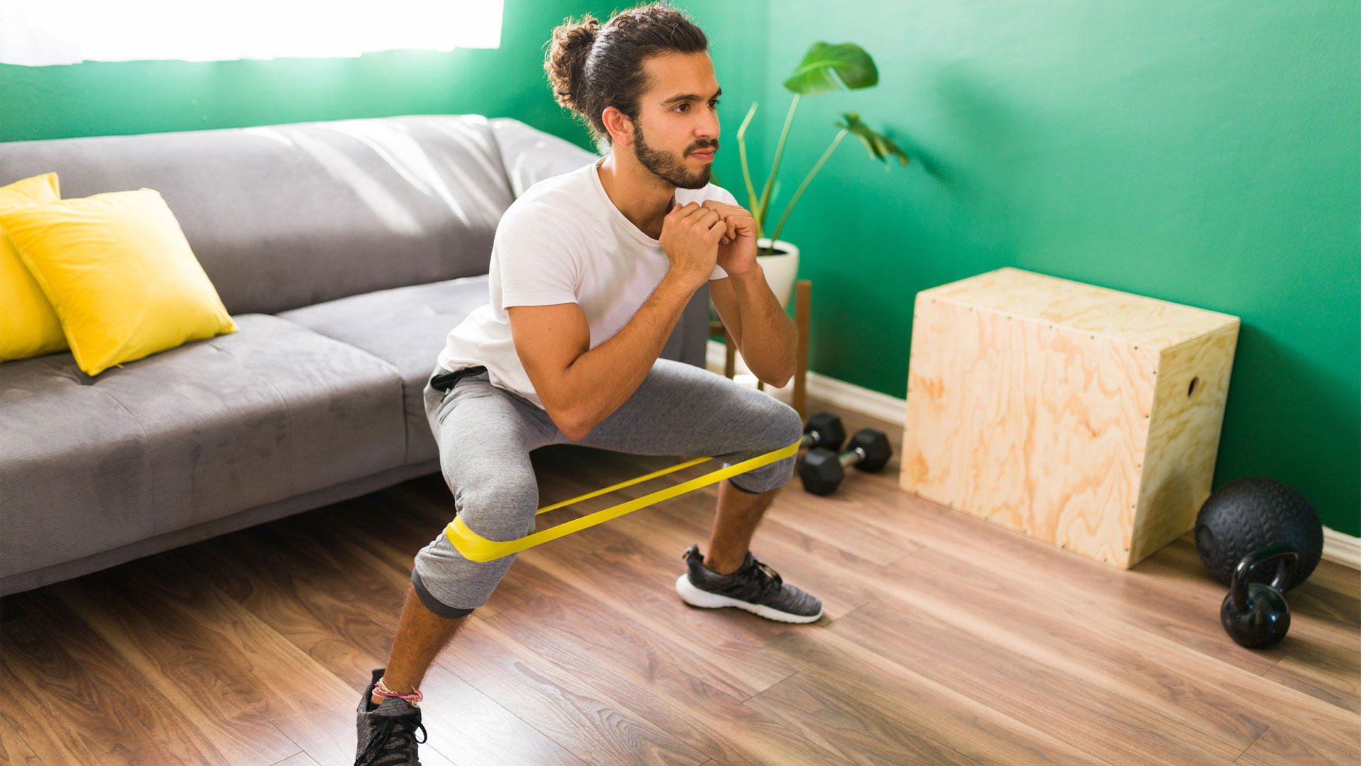 Comment faire des squats avec des bandes de résistance: l'homme faisant des squats avec des bandes de résistance