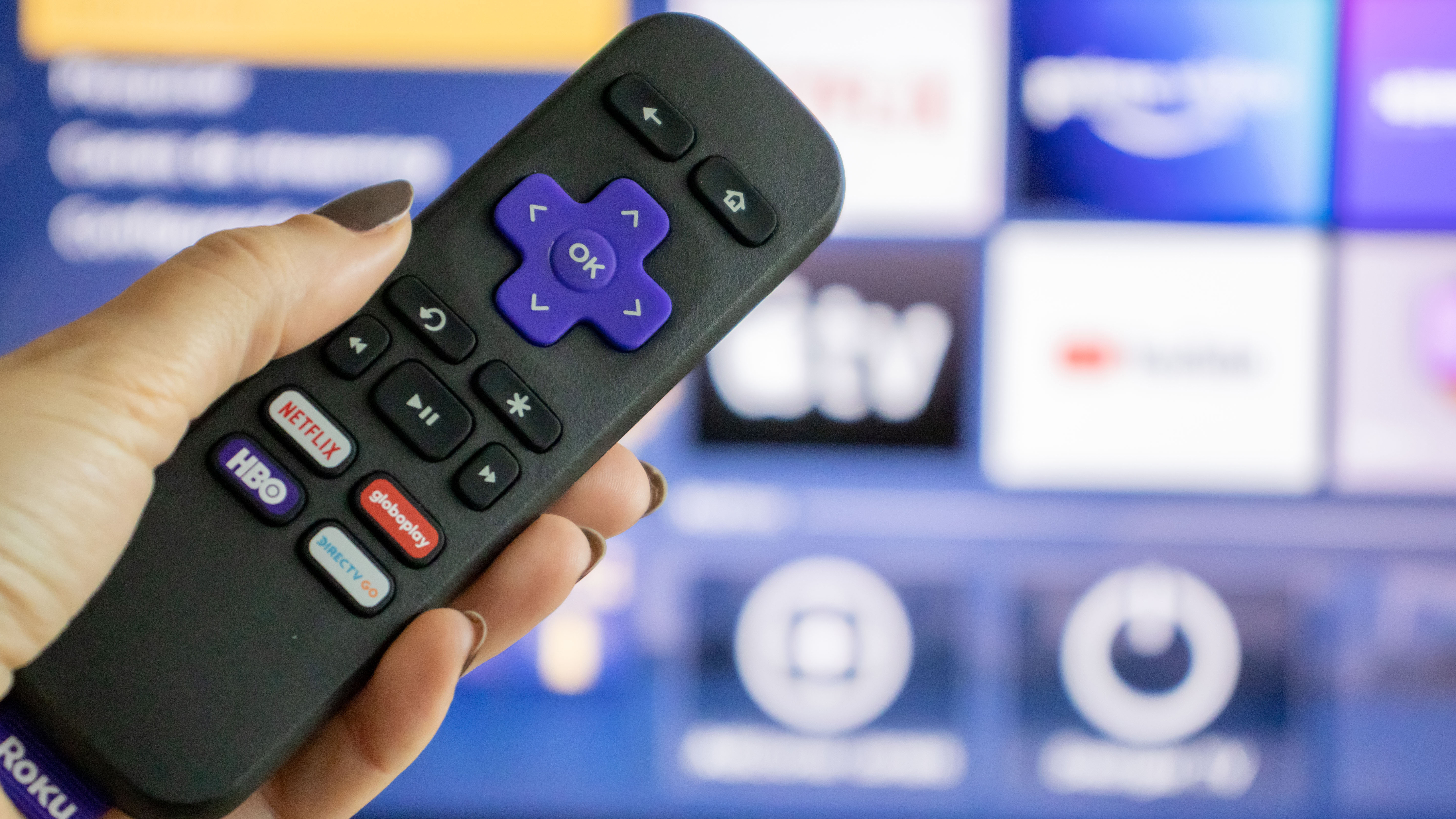 Recku Remote avec un bouton Netflix entre autres devant un téléviseur.