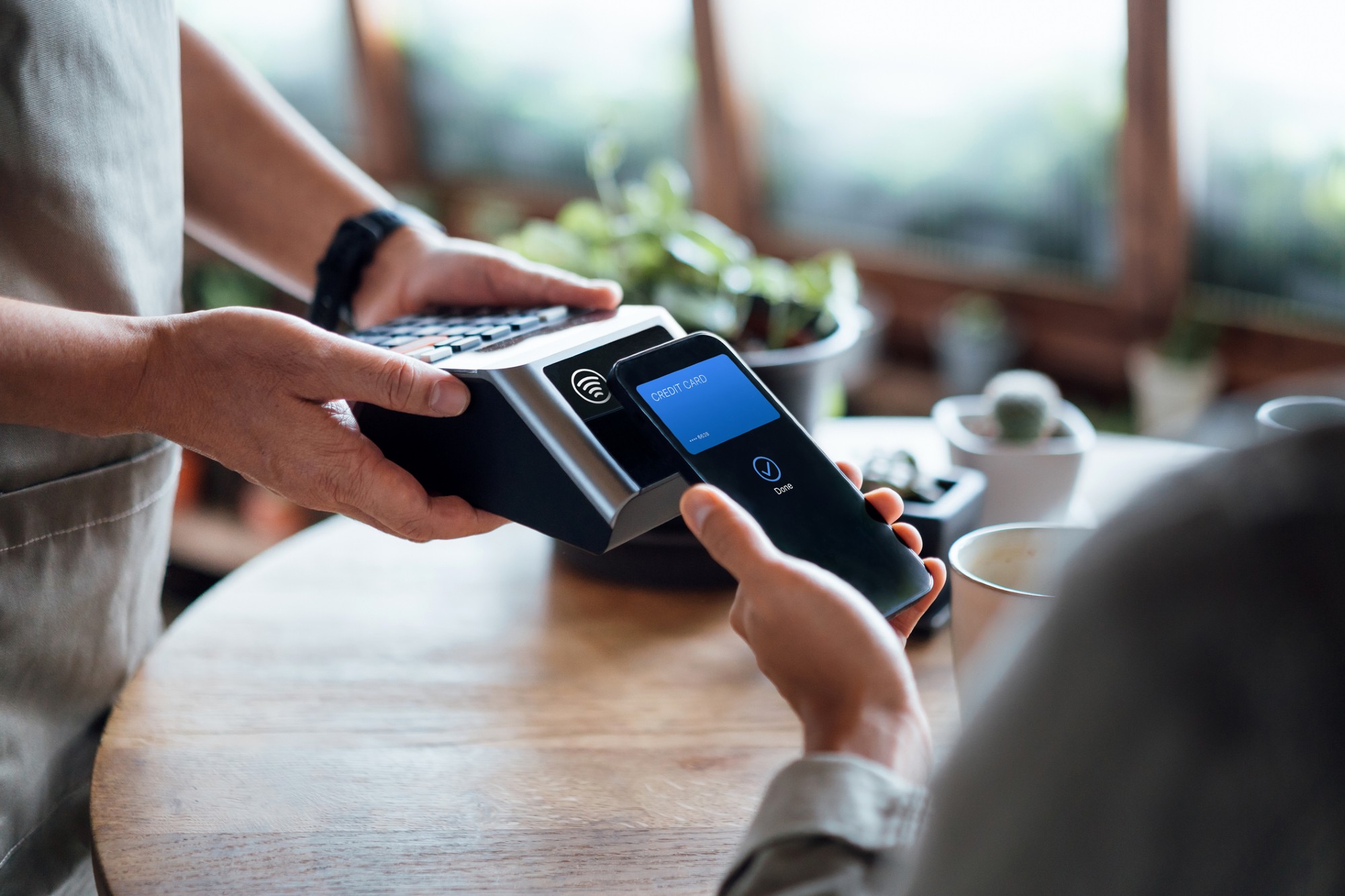 Gros plan d'une facture de paiement à la main d'un homme avec un paiement sans contact sur carte de crédit sur smartphone dans un café, en scannant sur une machine à cartes