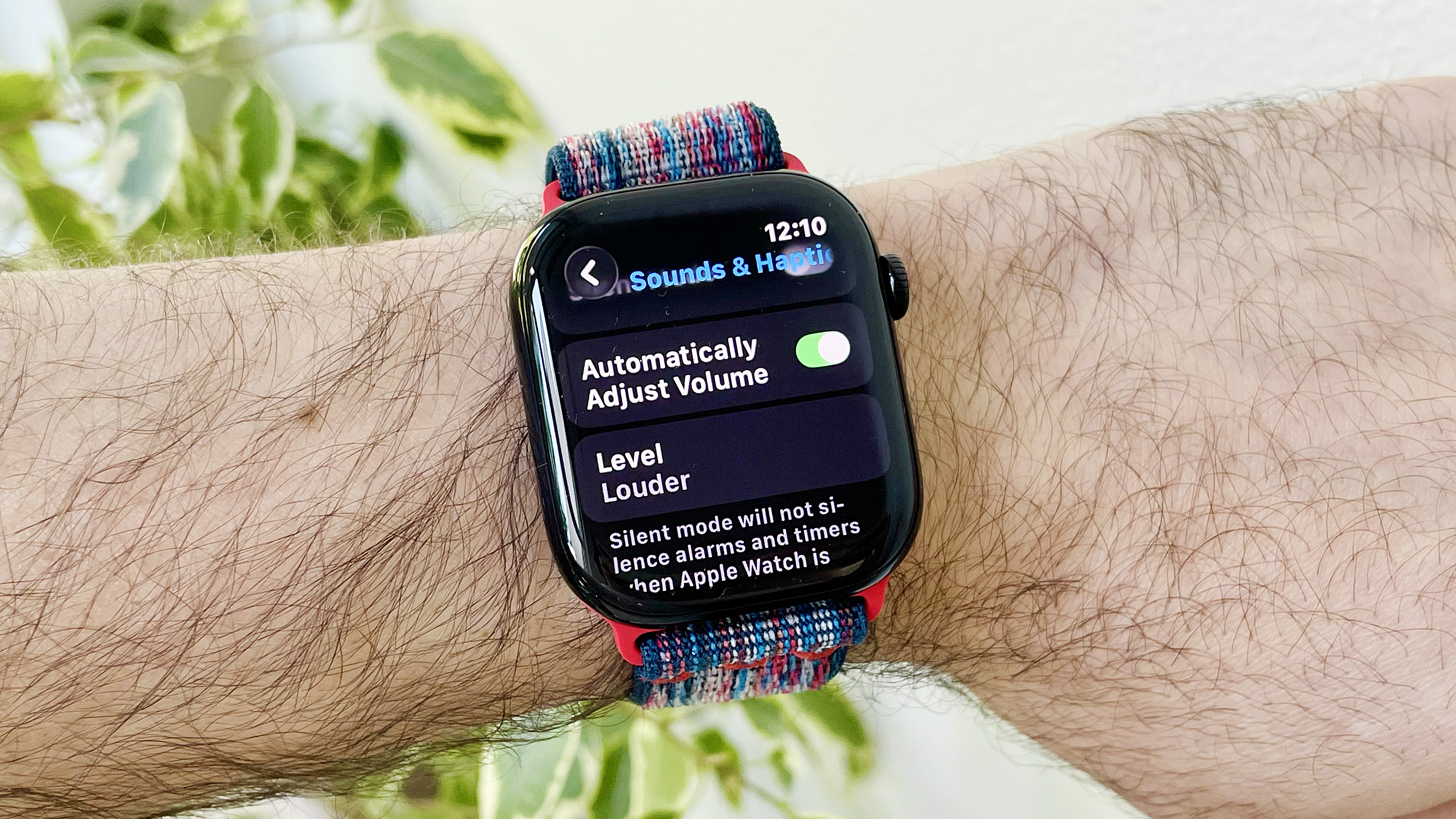 Gros plan du poignet d'un utilisateur portant l'Apple Watch Series 10 exécutant le dernier logiciel WatchOs 26. L'écran affiche le nouveau réglage des ajustements audio automatiques