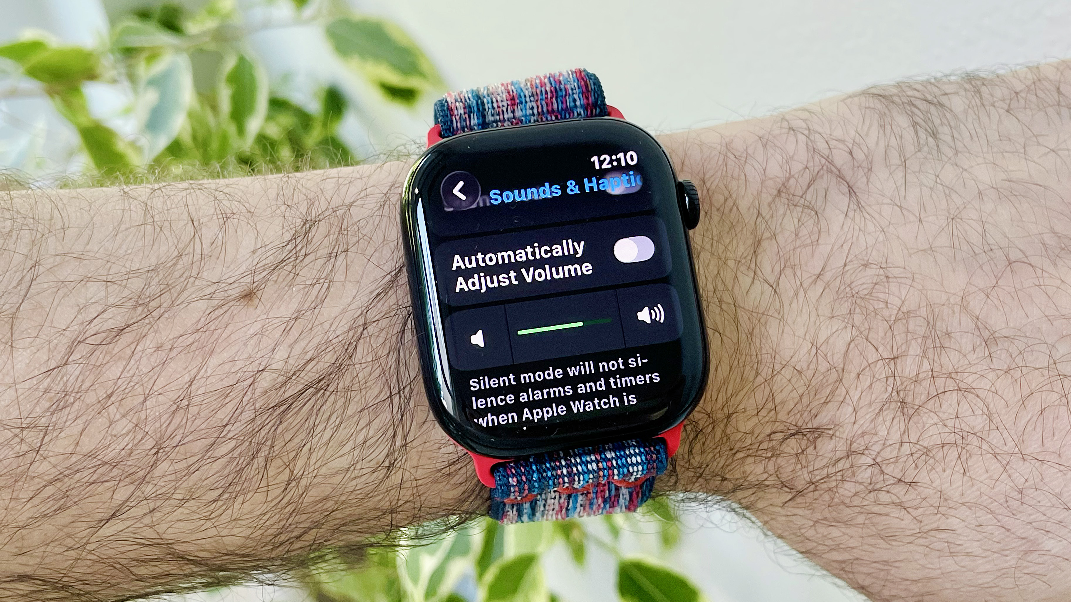 Gros plan du poignet d'un utilisateur portant l'Apple Watch Series 10 exécutant le dernier logiciel WatchOs 26. L'écran affiche le nouveau réglage des ajustements audio automatiques
