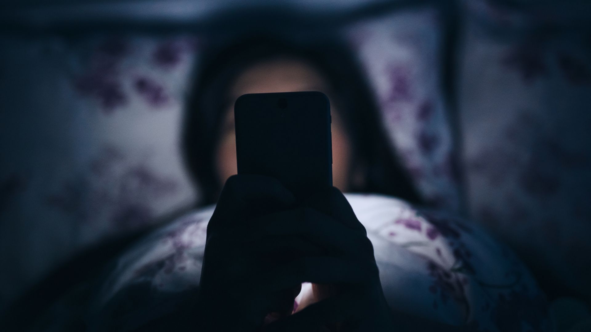 Une jeune femme fait défiler son téléphone la nuit