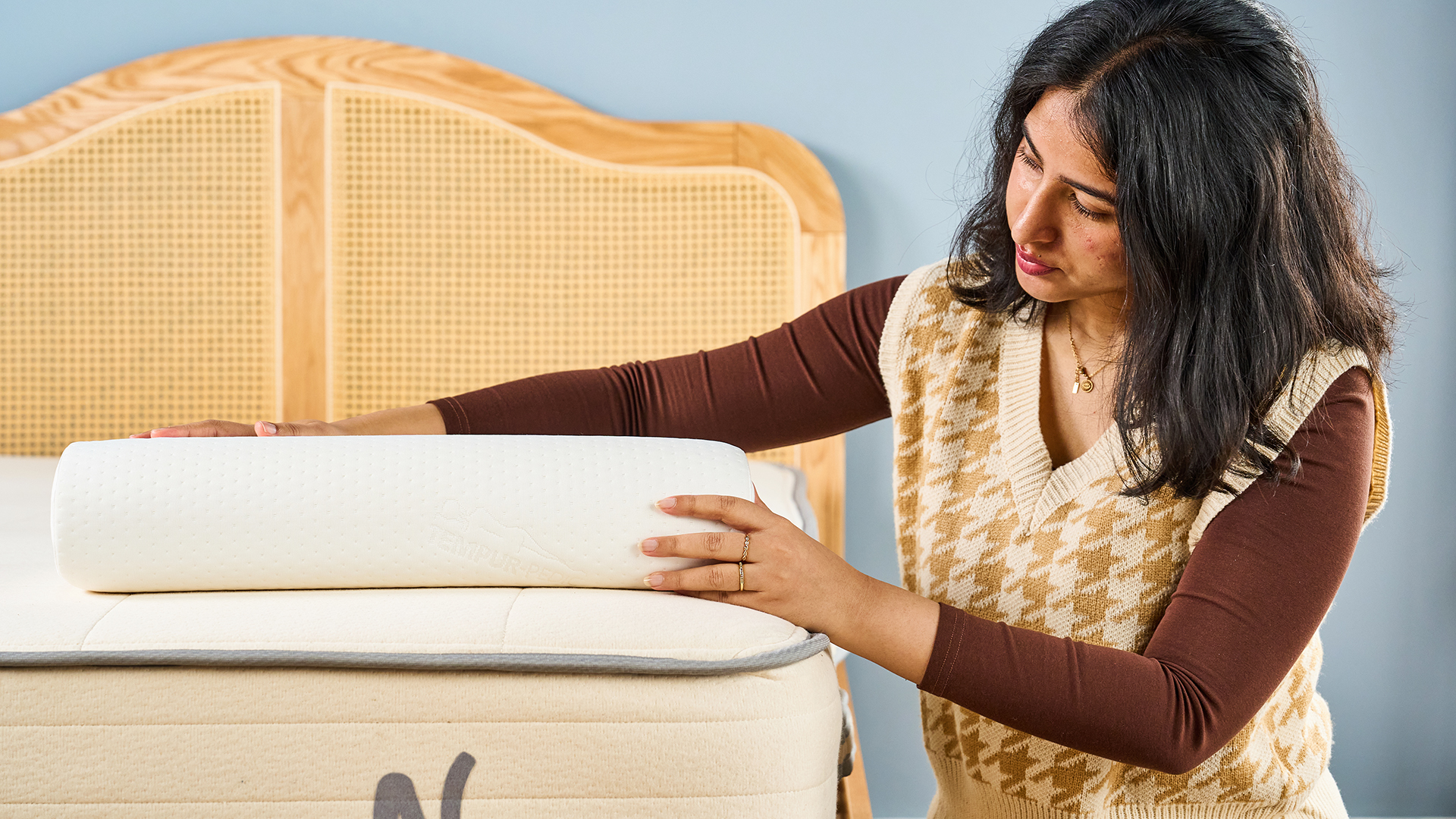 Femme plaçant sa main sur une chambre blanche incurvée sur le contexte d'une tête de lit en bois en bois du lit