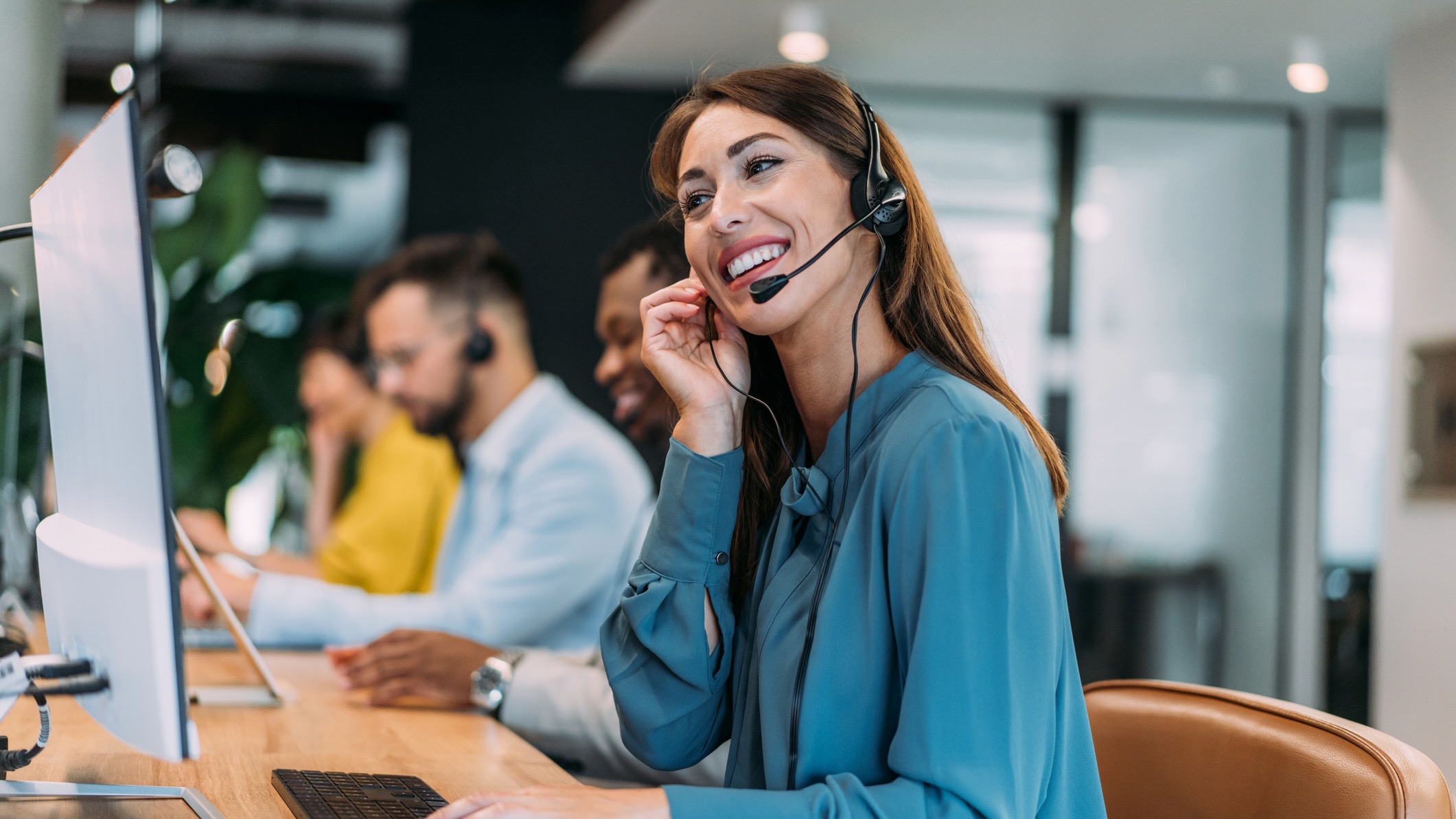 Femme aux cheveux noirs utilisant un casque à un bureau pour soutenir un client par téléphone