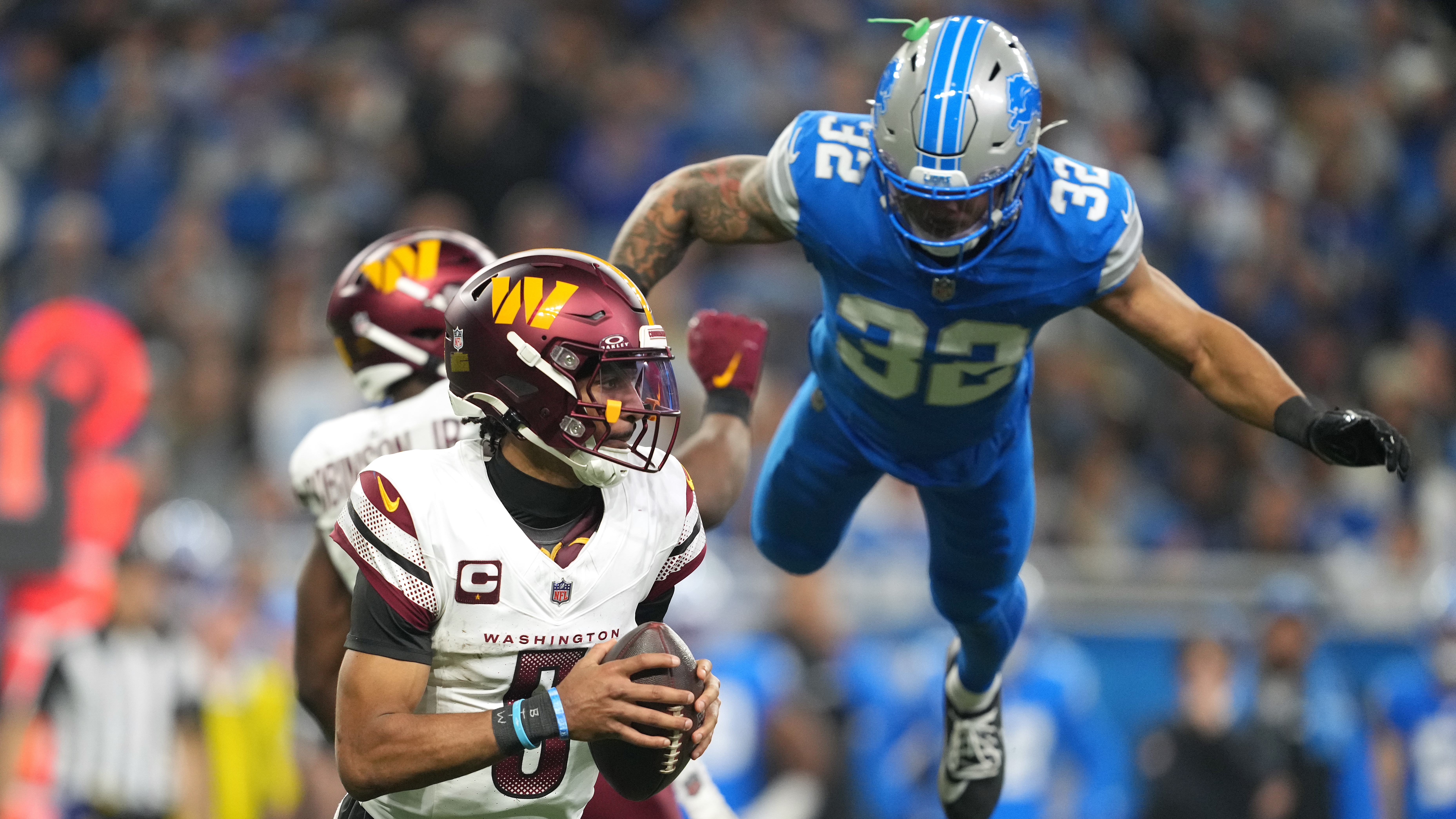 Jayden Daniels #5 des Washington Commanders se démène avec le ballon alors que Brian Branch #32 des Detroit Lions plonge pour faire pression au cours du troisième quart des éliminatoires de la division NFC au Ford Field le 18 janvier 2025 à Detroit, Michigan.
