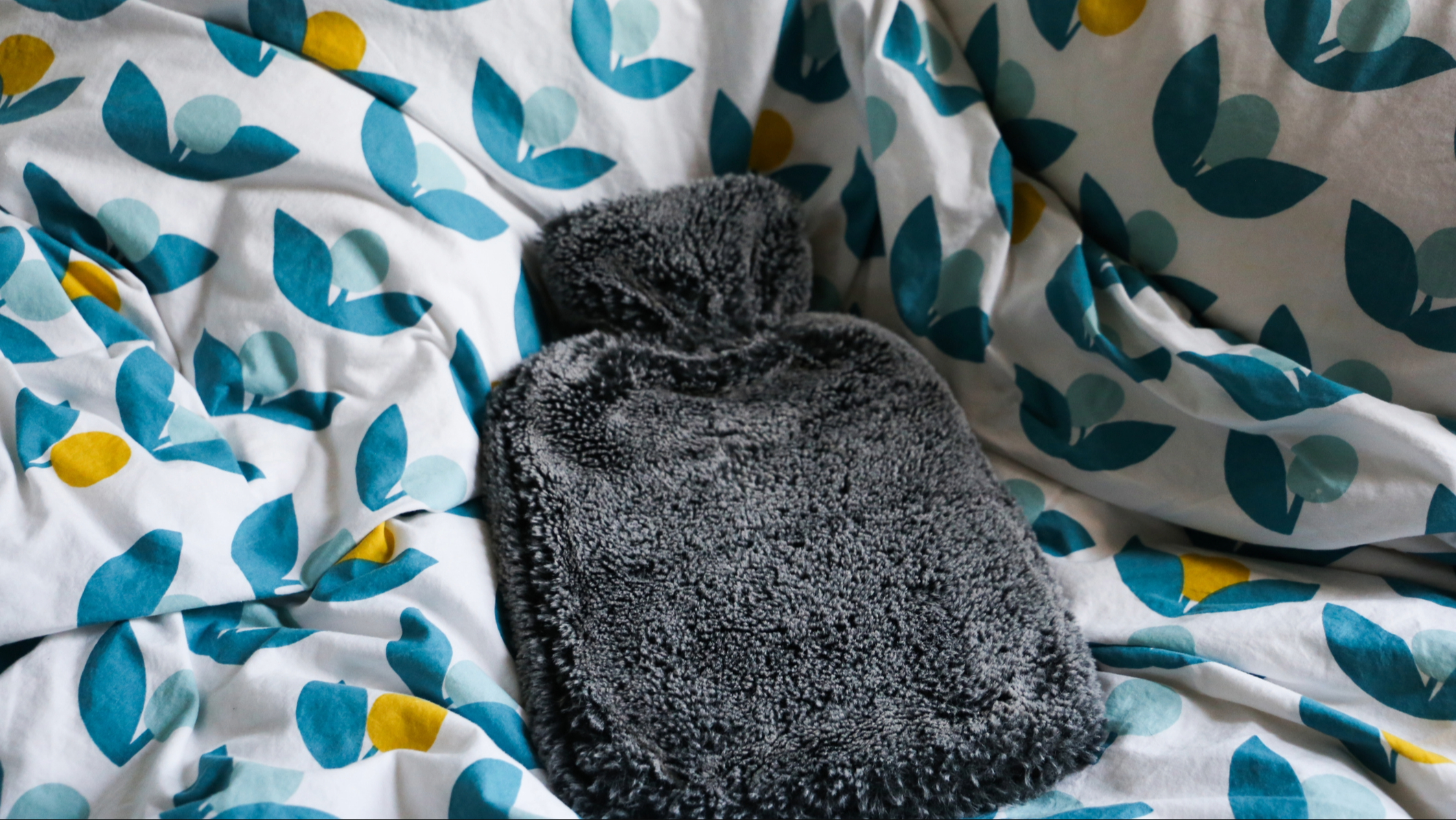 Bouillotte sur une couette à motifs fleuris