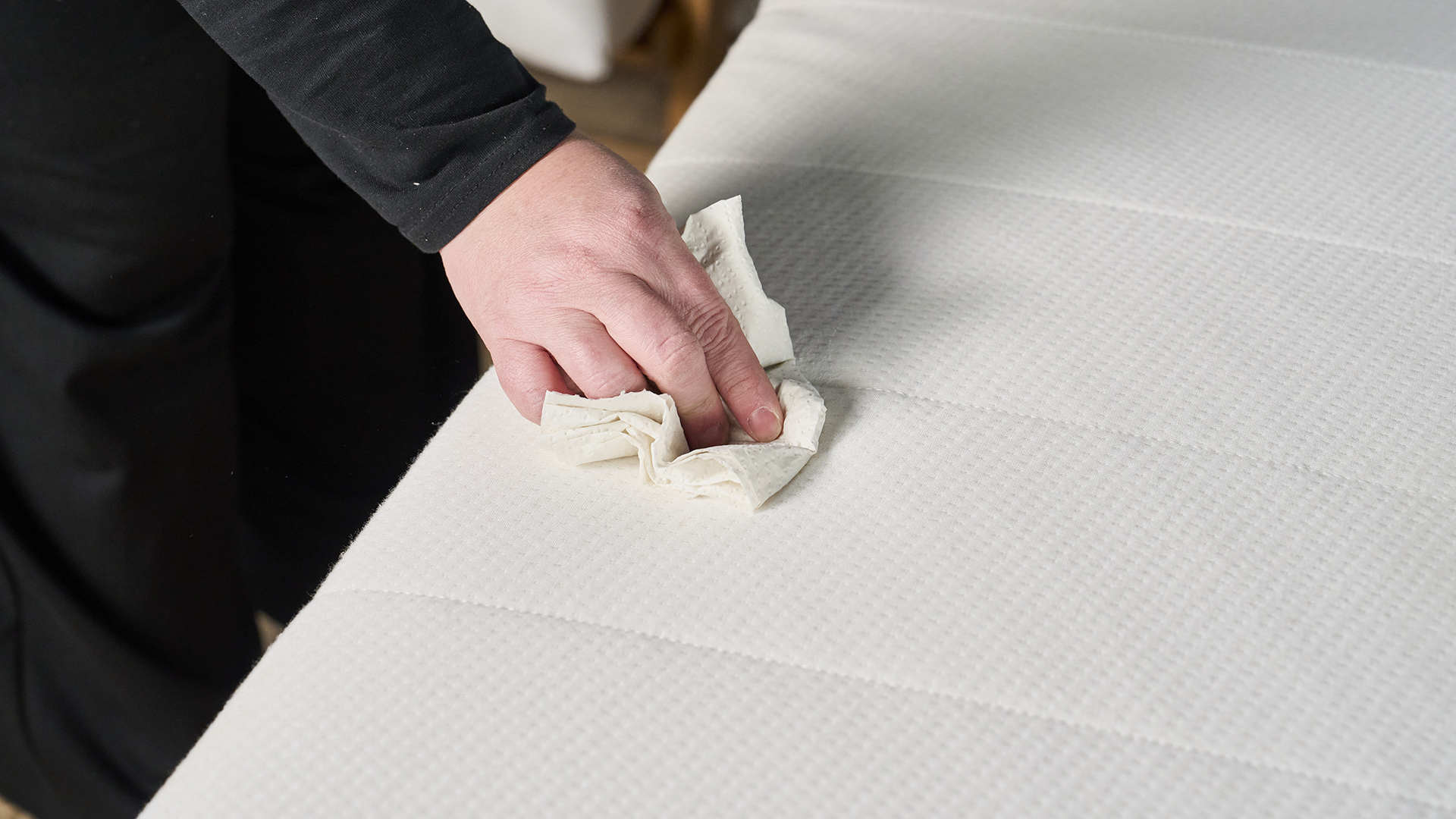 Une femme épongeant un matelas avec une serviette en papier