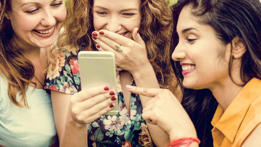 femmes riant de quelque chose au téléphone