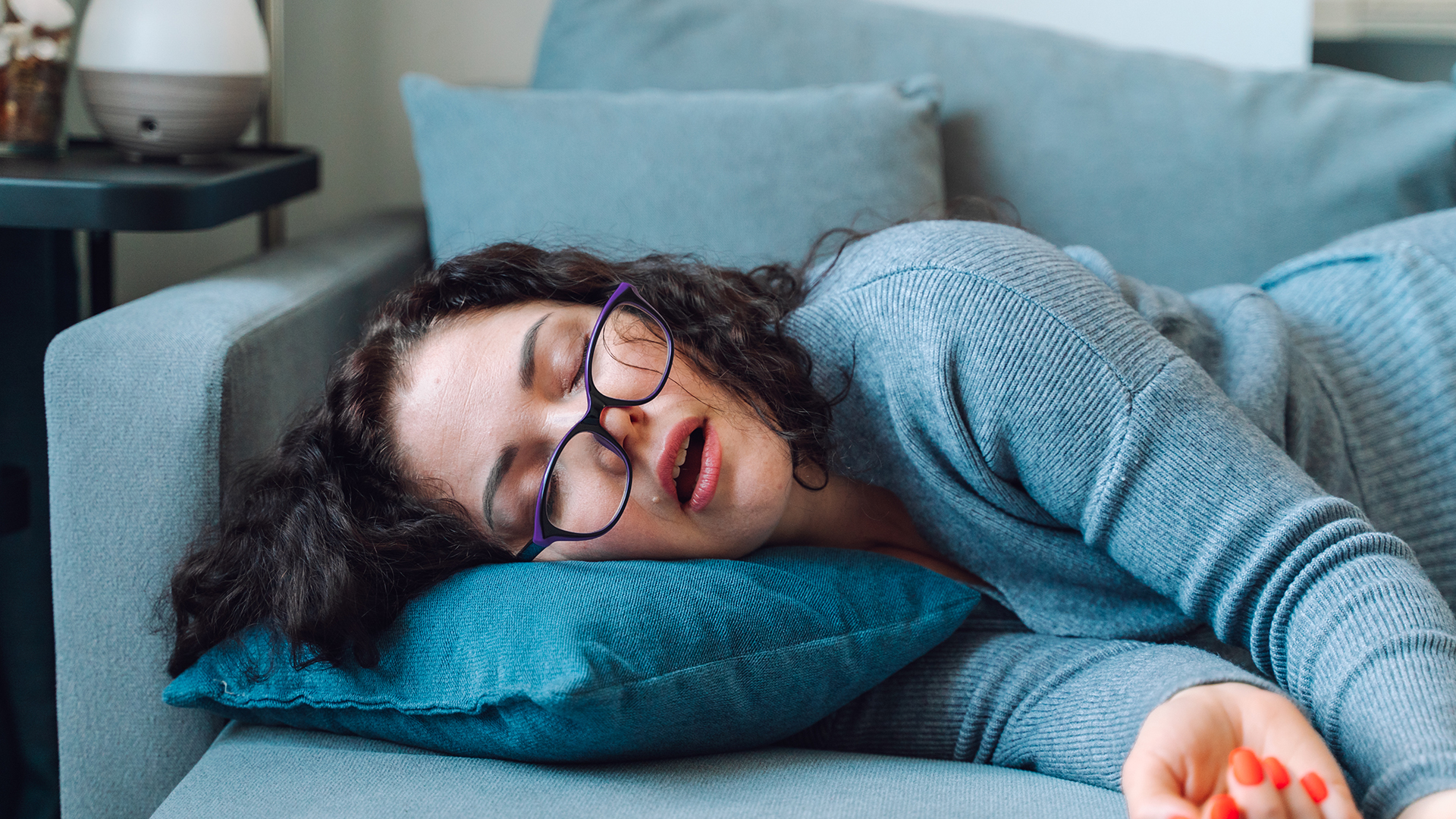 Une femme fait une sieste sur le canapé en pleine journée