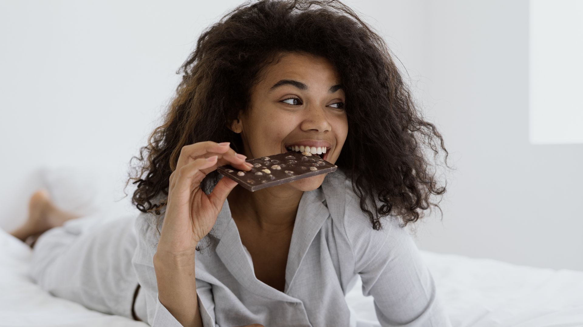 Une jeune femme mange du chocolat avant de se coucher