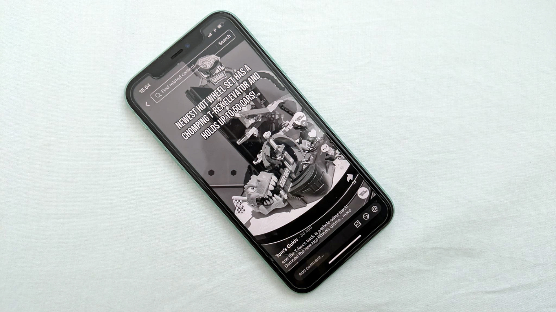 Image d'un iPhone 11 contre un oreiller, montrant la page TikTok de Tom's Guide en niveaux de gris