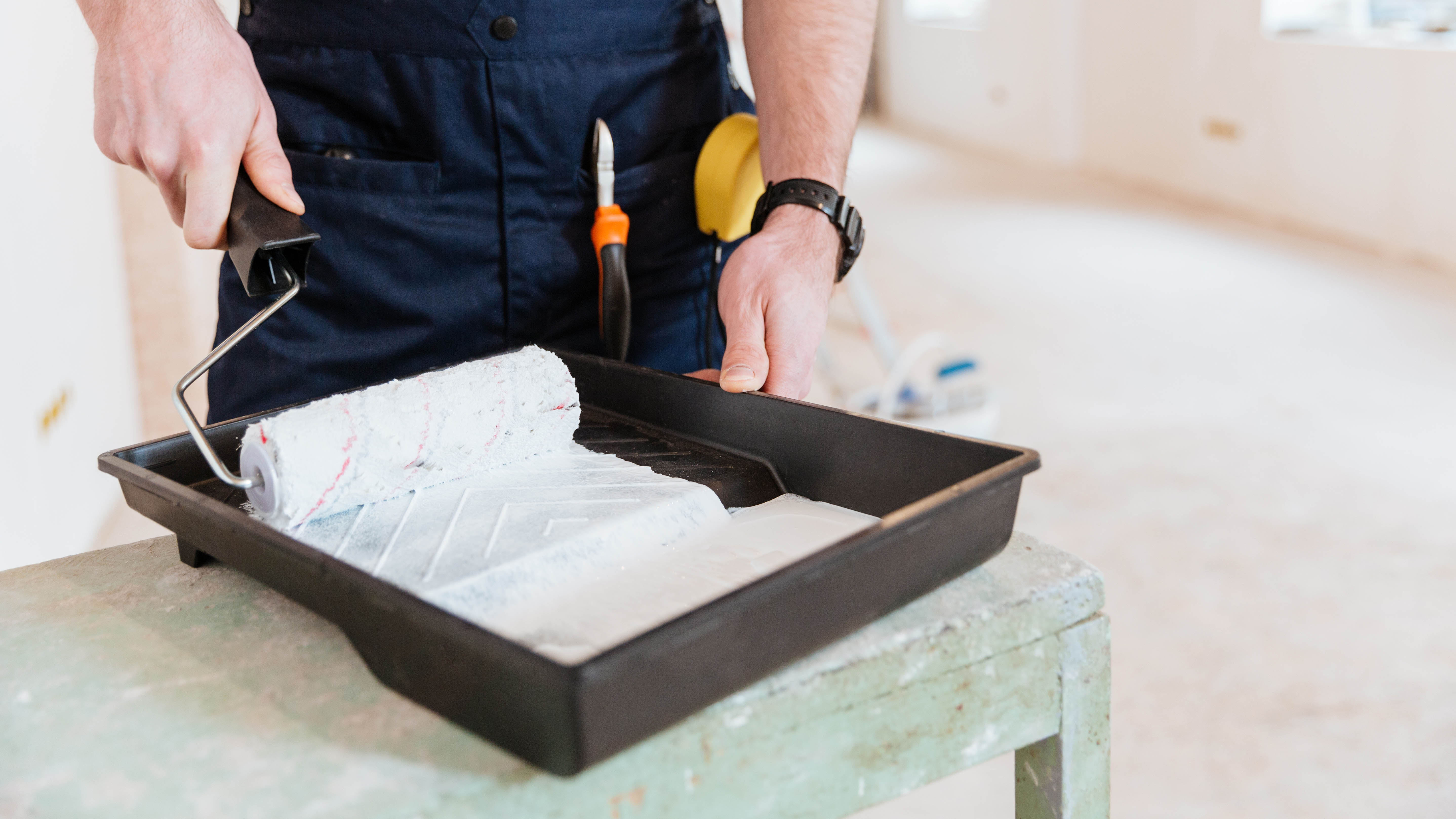 Un plateau rempli de peinture blanche avec un rouleau sur un dessus de table