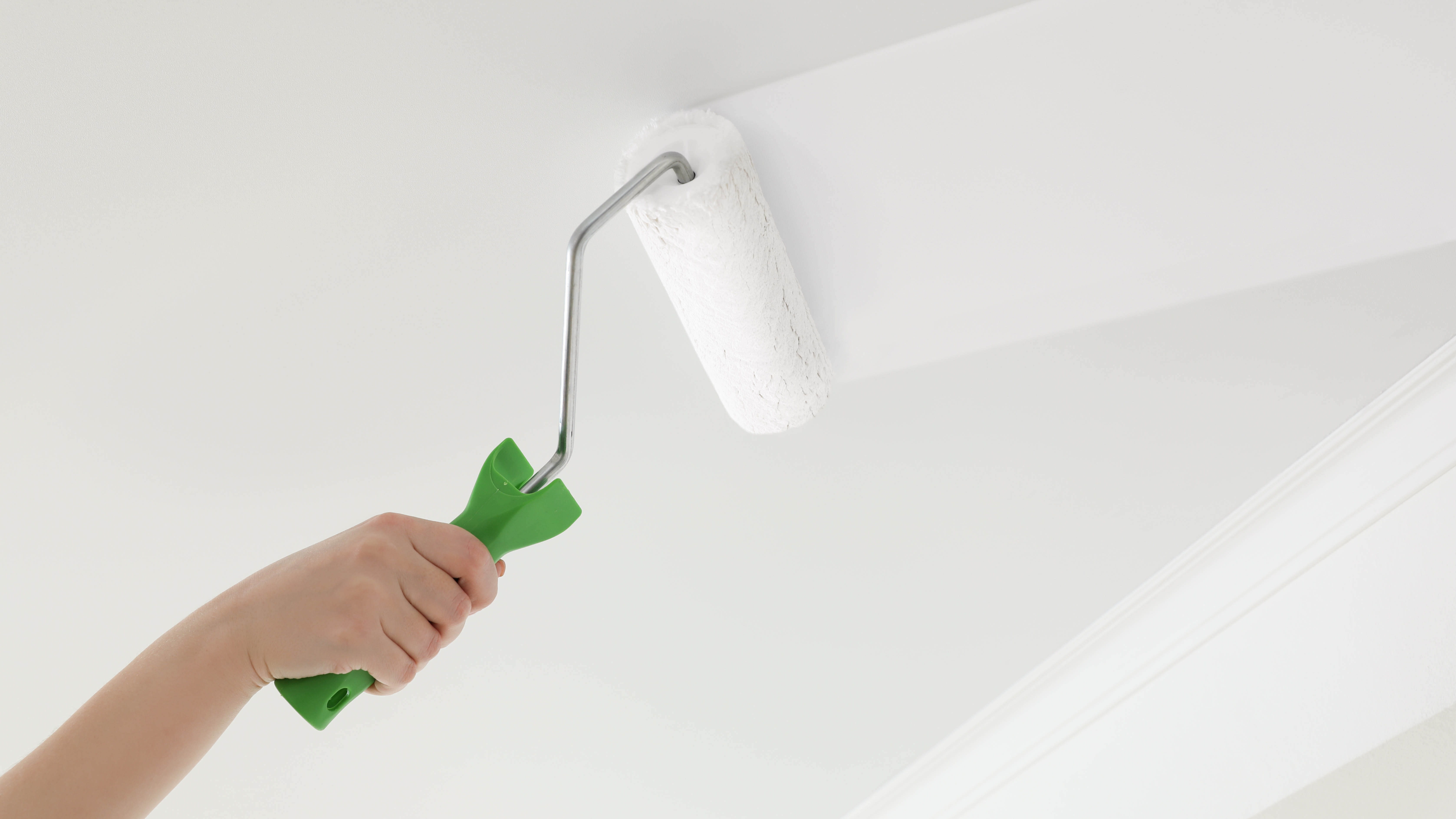 Un rouleau peignant de la peinture blanche sur un plafond