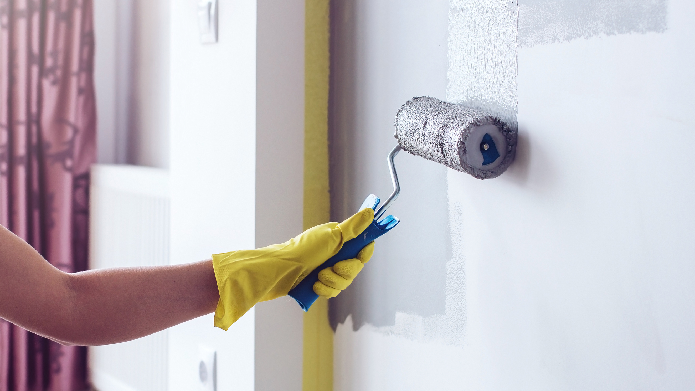 Femme peignant un mur avec un rouleau
