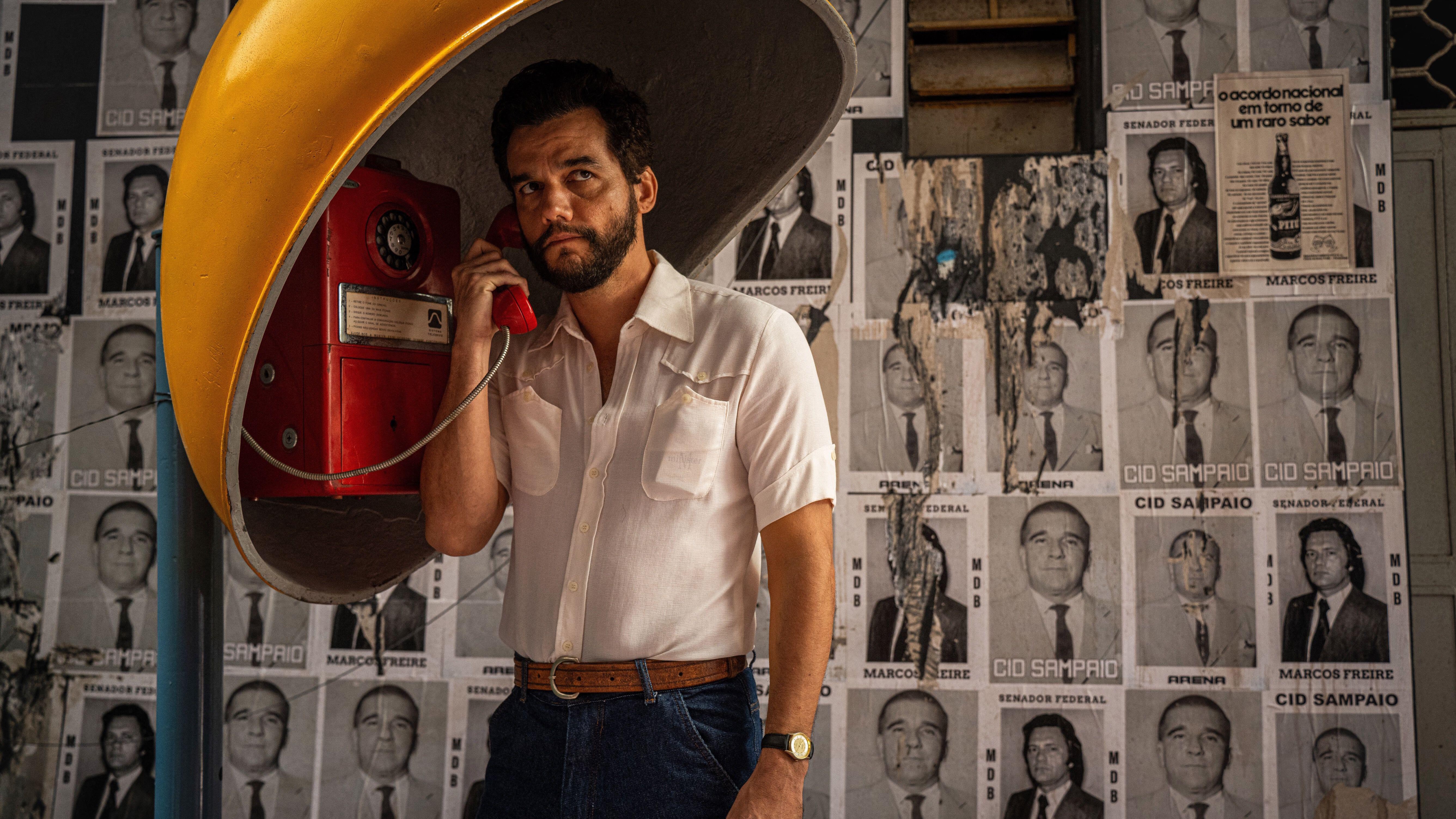 Wagner Moura utilisant un téléphone public dans une photo promotionnelle pour