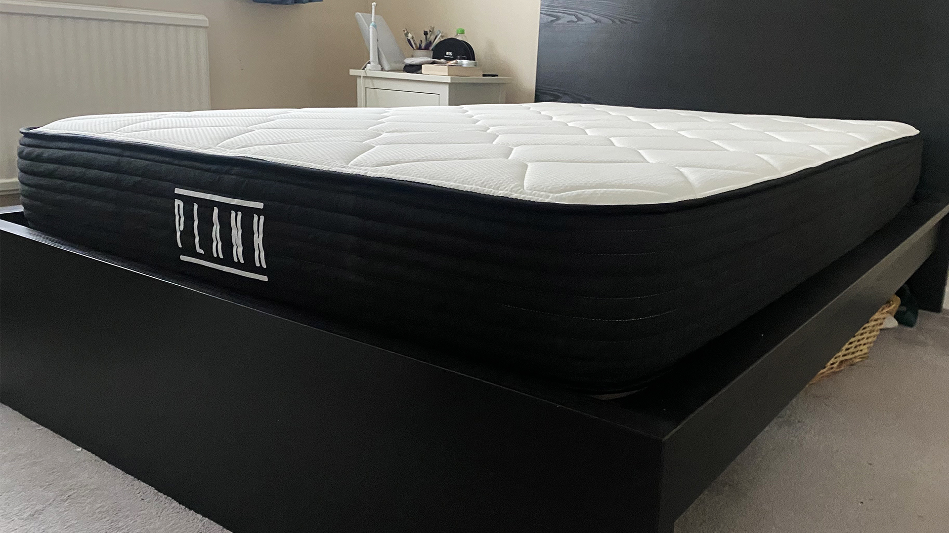 Le matelas Plank Firm (avec le côté Extra Firm tourné vers le haut) sur un cadre de lit noir dans la chambre de notre critique