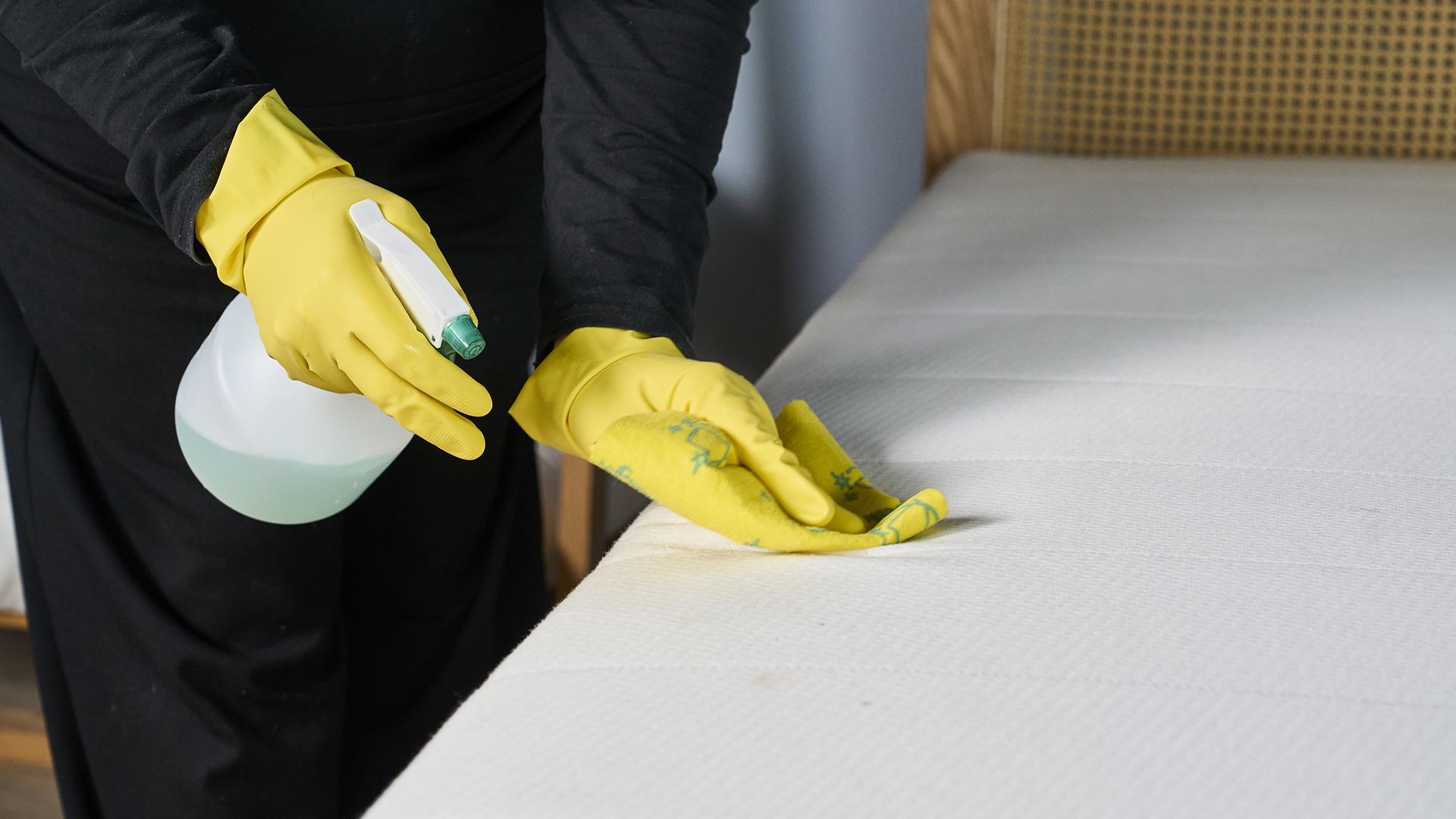 Un membre de l'équipe du sommeil de Tom's Guide pulvérise un matelas avec une solution antitache