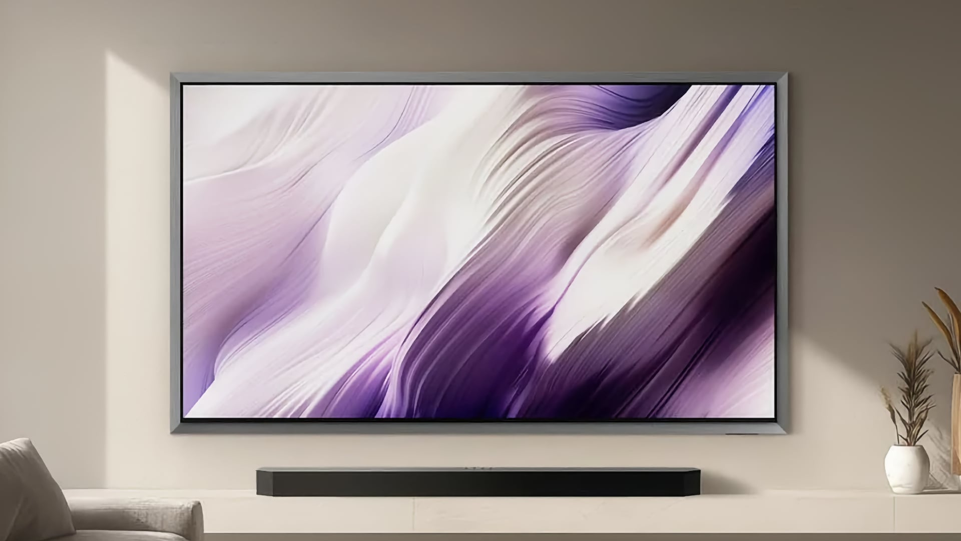 Le téléviseur OLED Samsung S99H affiche des images colorées et abstraites tout en étant fixé au mur dans un salon moderne au-dessus d'une barre de son
