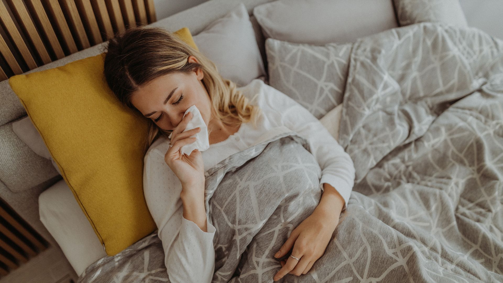 Une femme atteinte du rhume des foins essuie le nez bouché au lit