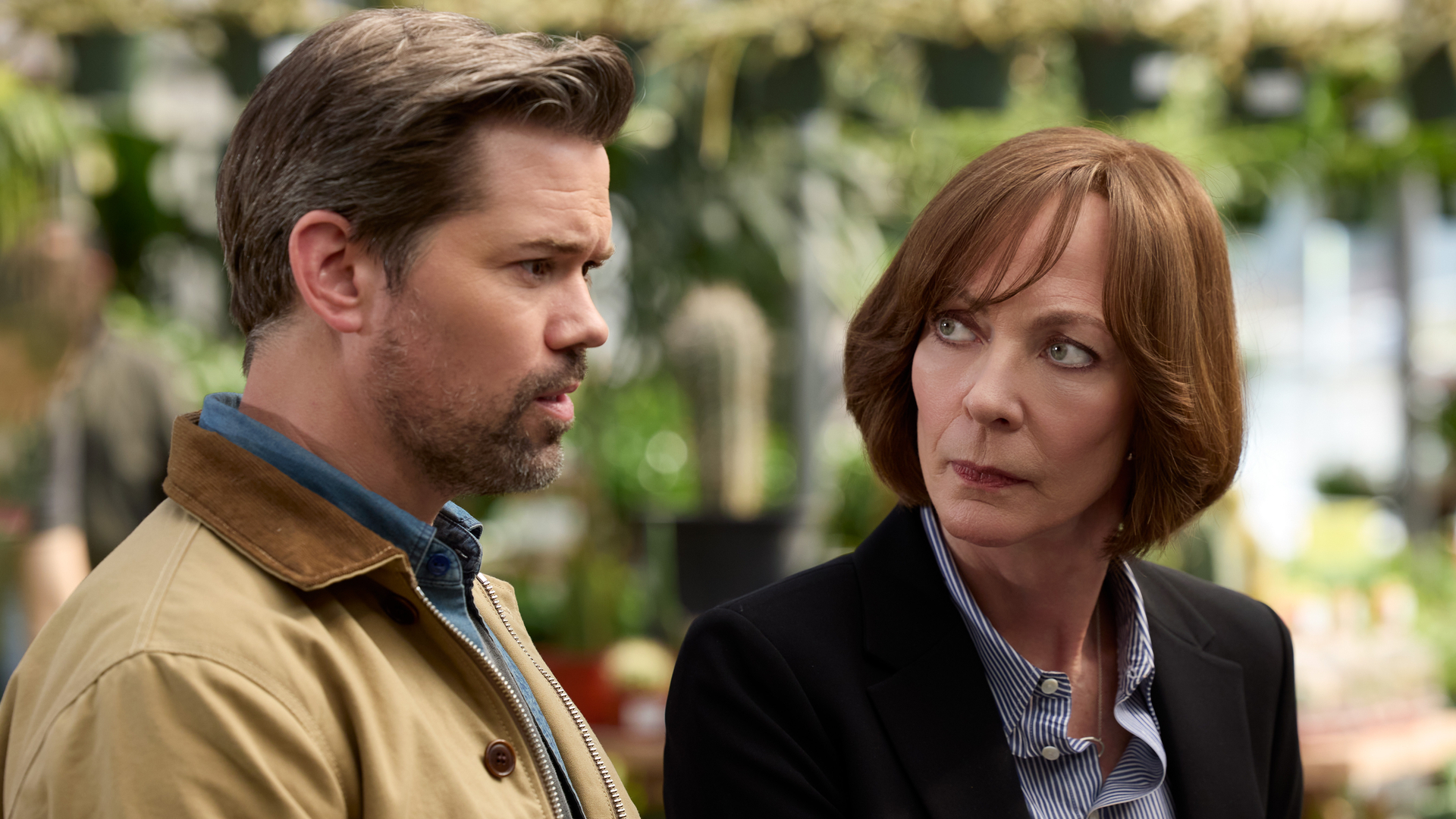 De gauche à droite : Andrew Rannells et Allison Janney sont assis ensemble à l'extérieur dans une scène de
