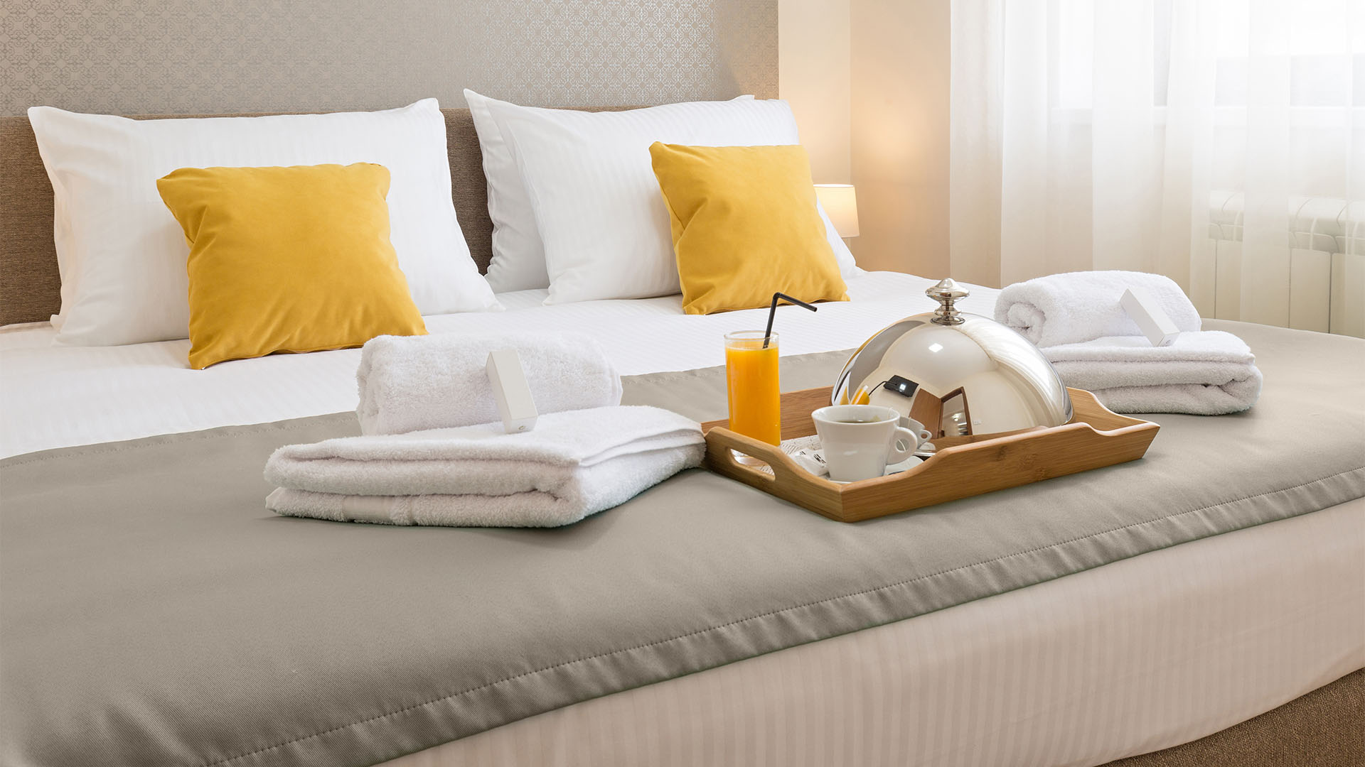 Un matelas dans un hôtel composé d'oreillers et de draps, de serviettes pliées et d'un plateau de petit-déjeuner sur le lit