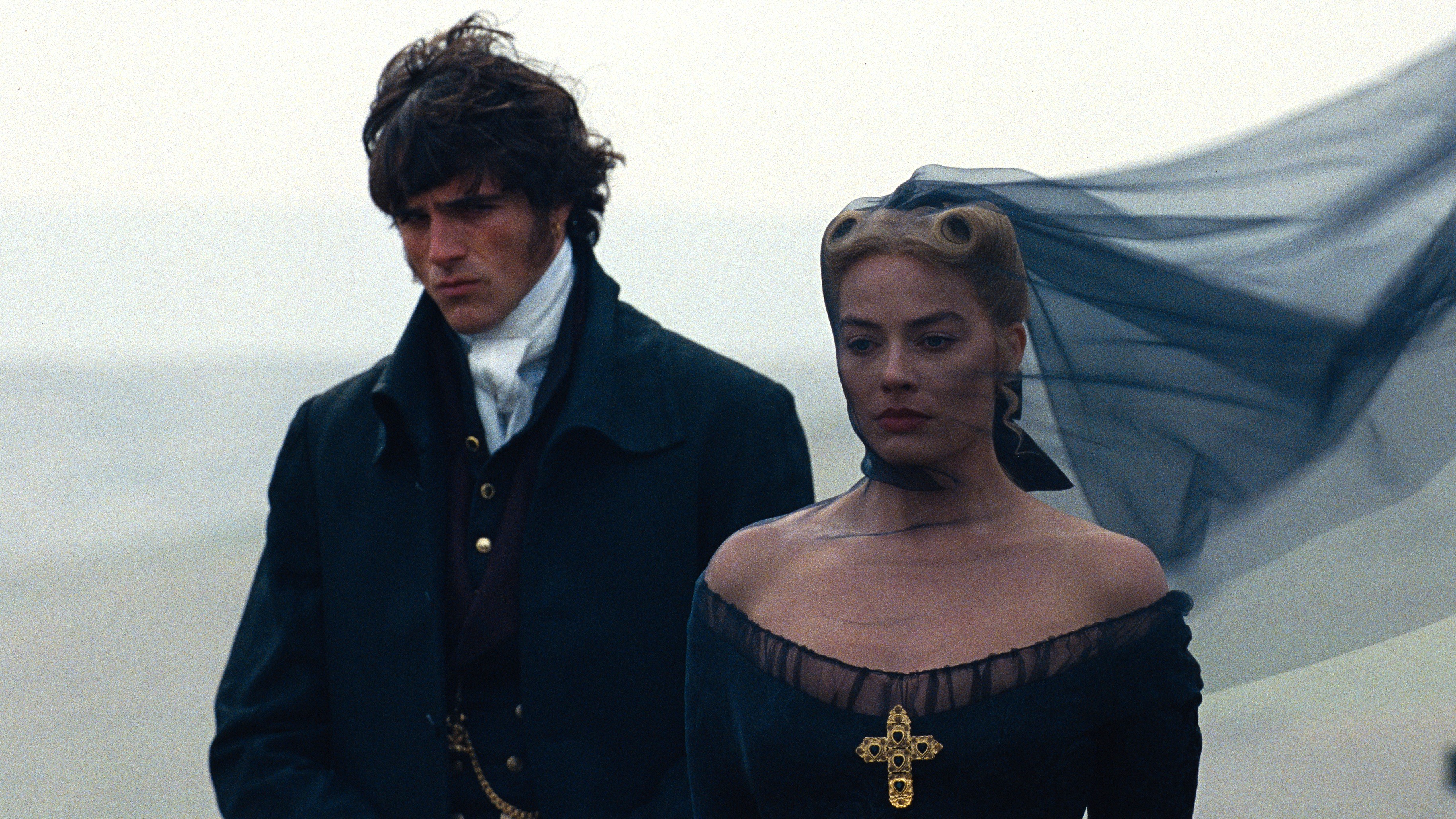 De gauche à droite : Heathcliff (Jacob Elordi) et Catherine Earnshaw (Margot Robbie) en tenue funéraire dans une scène de