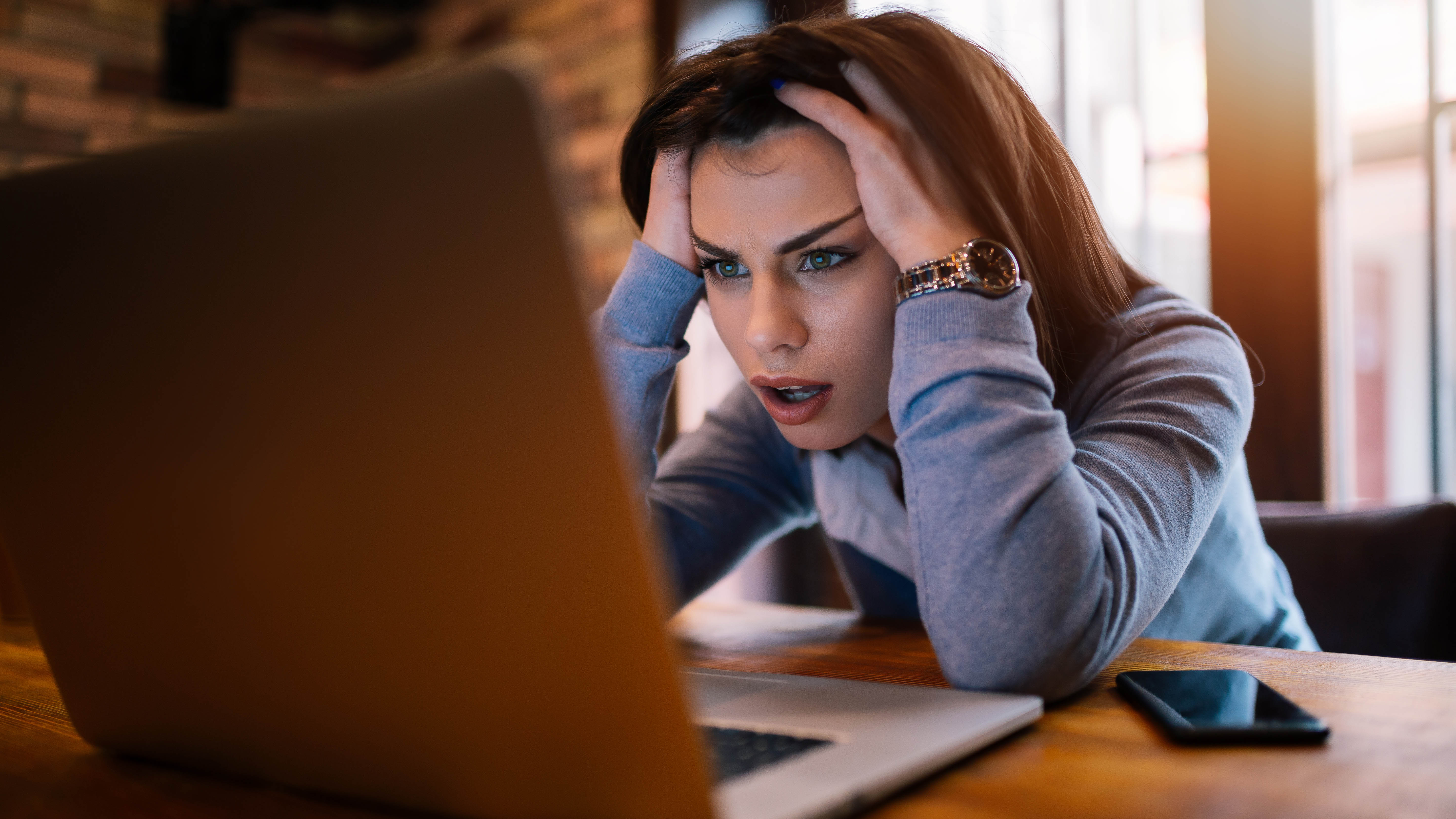 Une femme assise devant son ordinateur portable et semblant frustrée