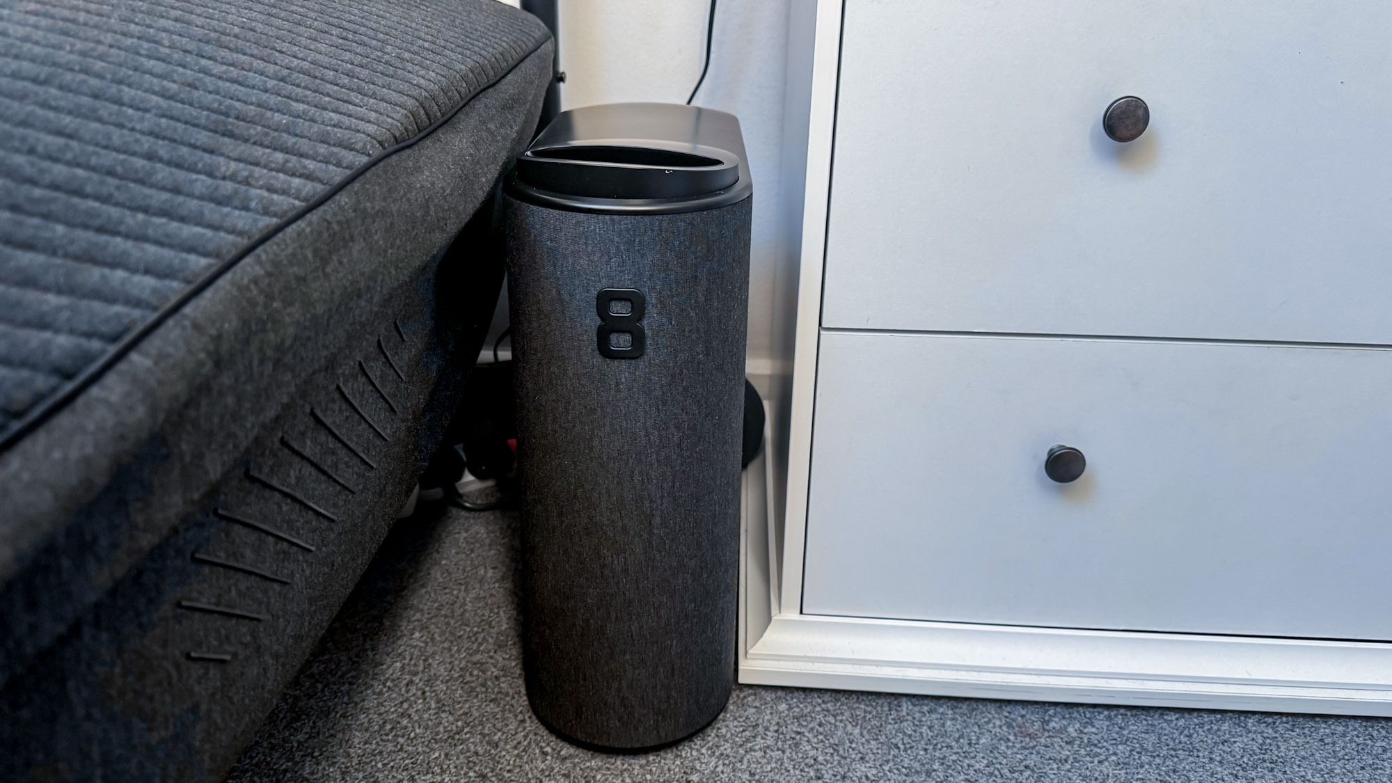 Eight Sleep Pod 4 hub de commande noir entre le lit et la commode blanche