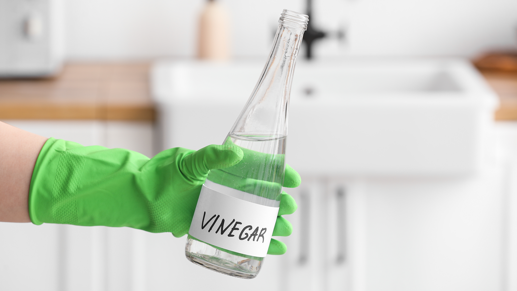 Main féminine tenant une bouteille de vinaigre