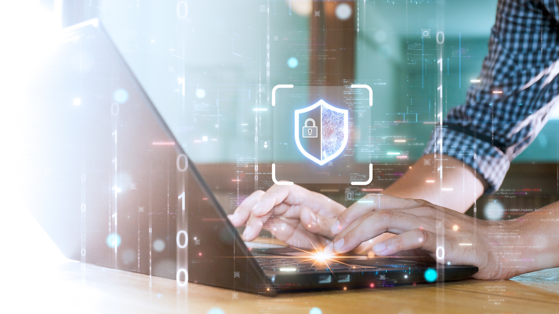 Mains tapant sur un ordinateur portable avec une icône de bouclier numérique et de verrouillage, symbolisant la cybersécurité. Entouré de code binaire et d’éléments lumineux.