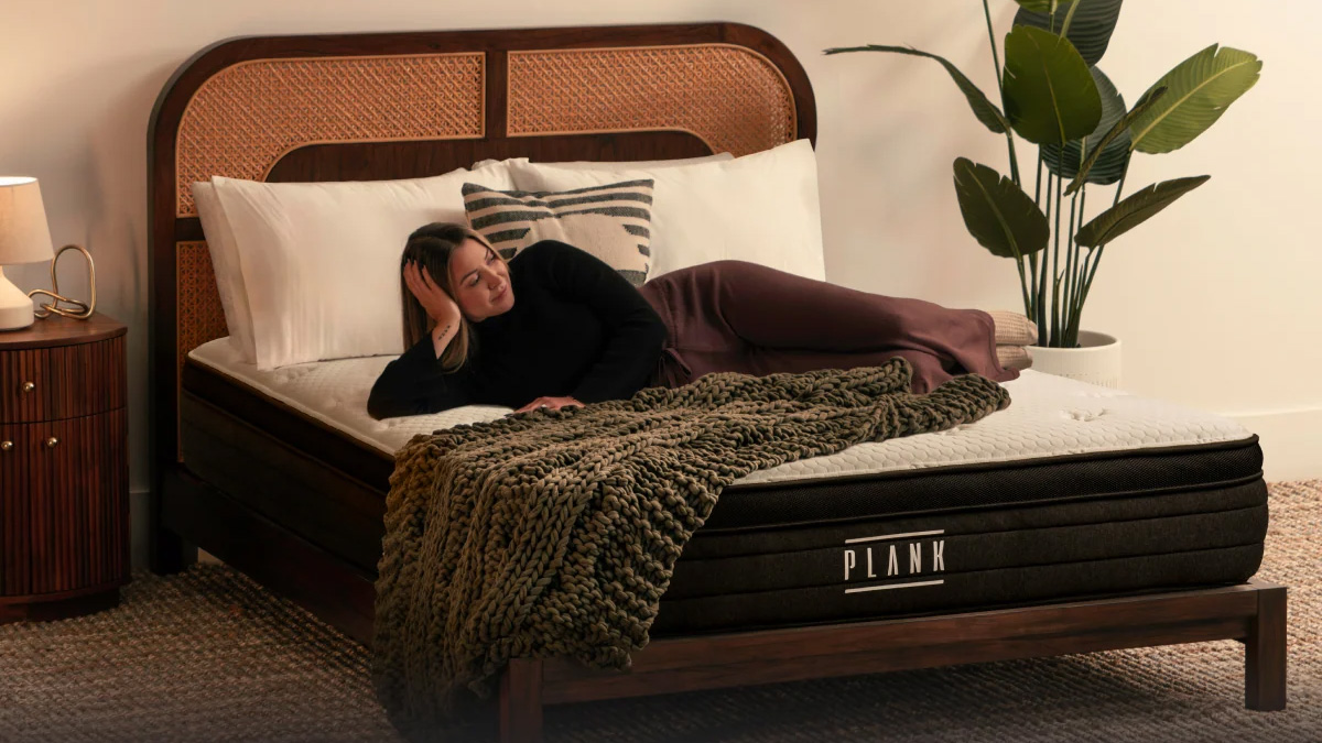 Une femme est allongée sur le matelas Plank Firm Rx dans une chambre chaleureusement éclairée